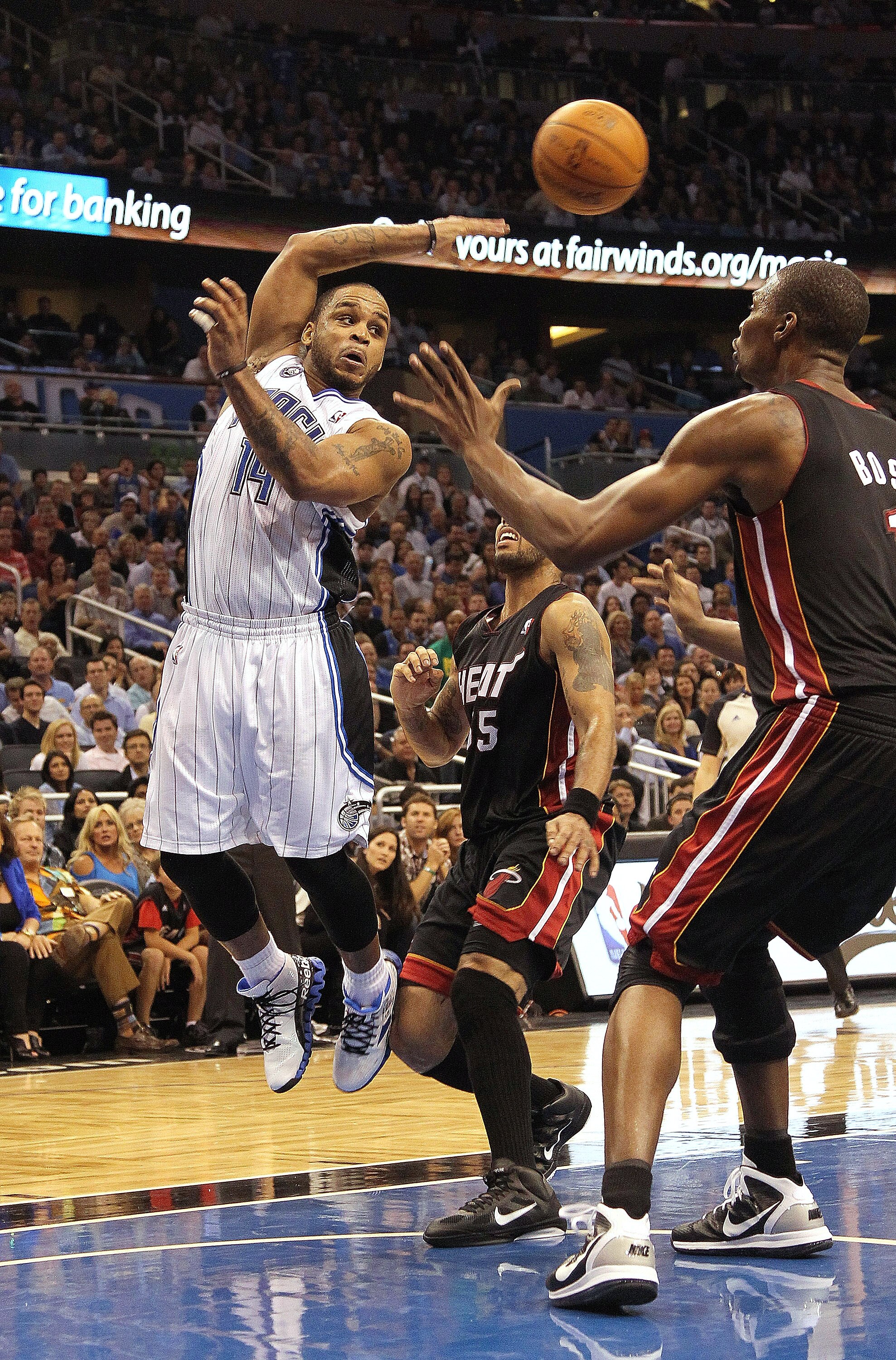 ORLANDO, FL - NOVEMBER 24: Jameer Nelson #14 of the Orlando Magic passes over Chris Bosh #1 of the Miami Heat during a game at Amway Arena on November 24, 2010 in Orlando, Florida. NOTE TO USER: User expressly acknowledges and agrees that, by downloading