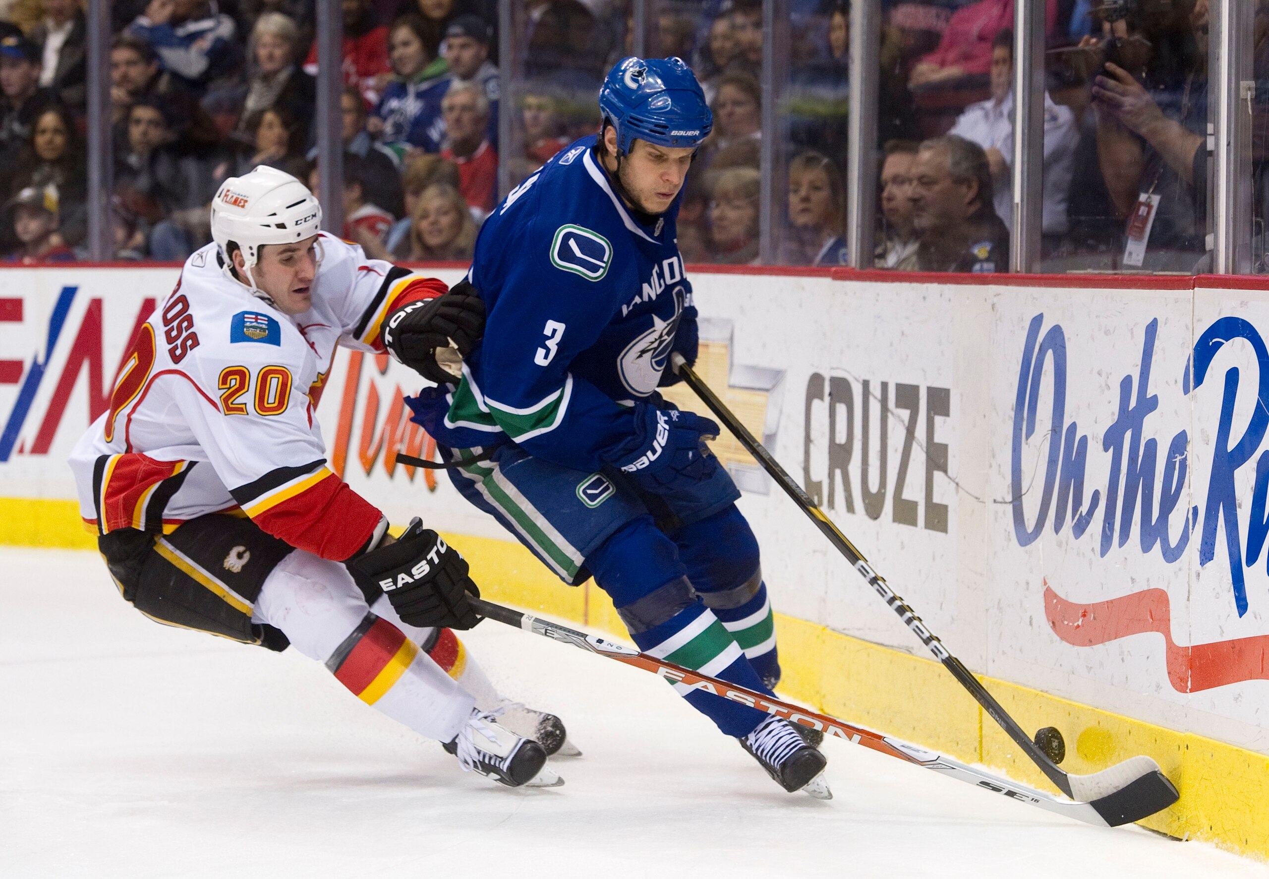 VANCOUVER, CANADA - JANUARY 5: Kevin Bieksa #3 of the Vancouver Canucks tries to control the bouncing puck while being checked by Curtis Glencross #20 of the Calgary Flames during the first period in NHL action on January 05, 2011 at Rogers Arena in Vanco VANCOUVER, CANADA - JANUARY 5: Kevin Bieksa #3 of the Vancouver Canucks tries to control the bouncing puck while being checked by Curtis Glencross #20 of the Calgary Flames during the first period in NHL action on January 05, 2011 at Rogers Arena in Vanco
