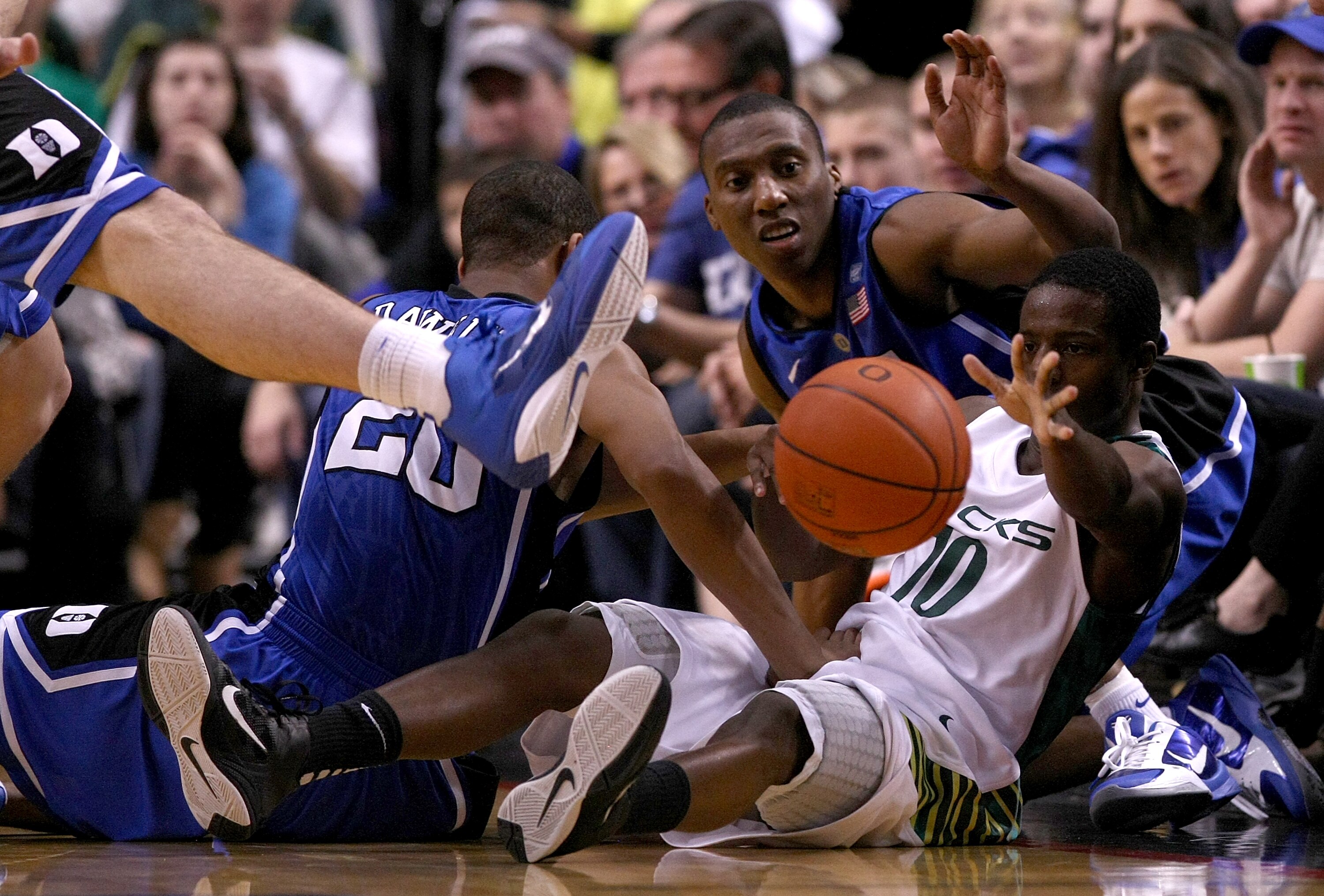 PORTLAND, OR - NOVEMBER 27:   Johnathan Loyd #10 of the Oregon Ducks is passes the ball form the ground against Andre Dawkins #20 and Nolan Smith #2 of the Duke Blue Devils on November 27, 2010 at the Rose Garden in Portland, Oregon.  (Photo by Jonathan F