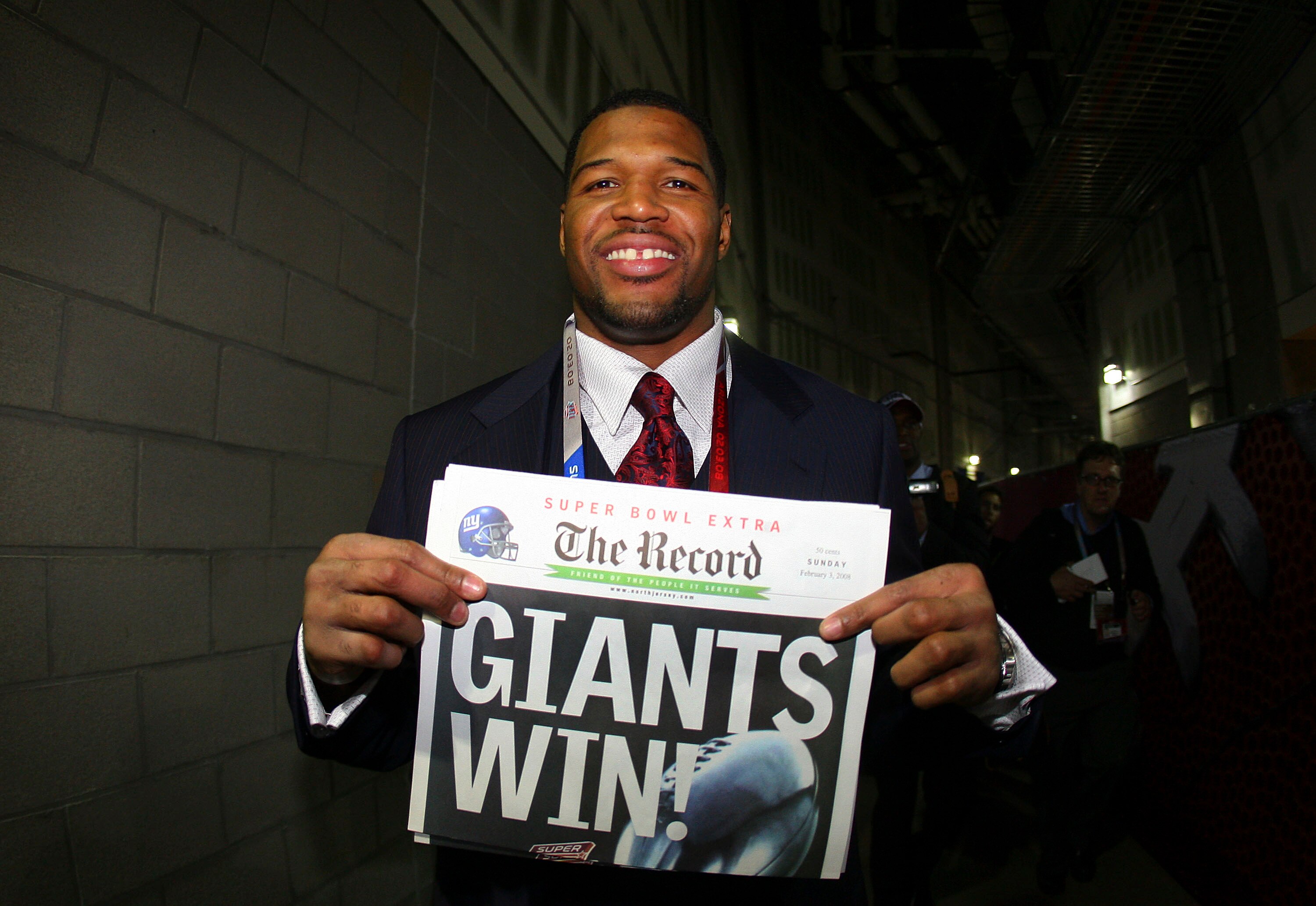 GLENDALE, AZ - FEBRUARY 03:  Defensive end Michael Strahan #92 of the New York Giants holds a copy of the Bergen Record with the headline 'GIANTS WIN!' after the Giants defeated the New England Patriots 17-14 during Super Bowl XLII on February 3, 2008 at