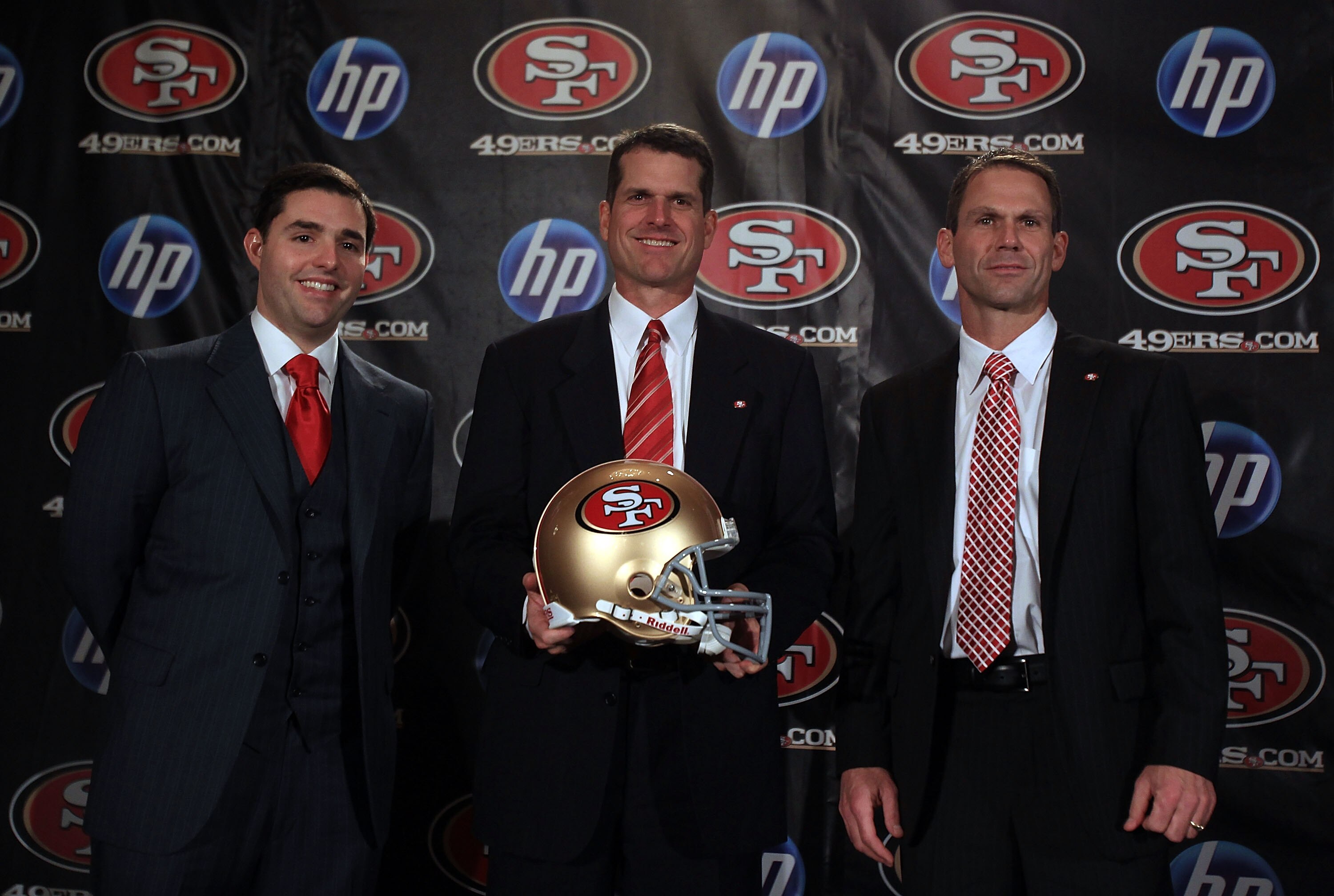 SAN FRANCISCO, CA - JANUARY 07:  Jim Harbaugh poses for a picture with President and CEO of the San Francisco 49ers, Jed York, (left) and general manager Trent Baalk following a press conference where Harbaugh was introduced as the new San Francisco 49ers