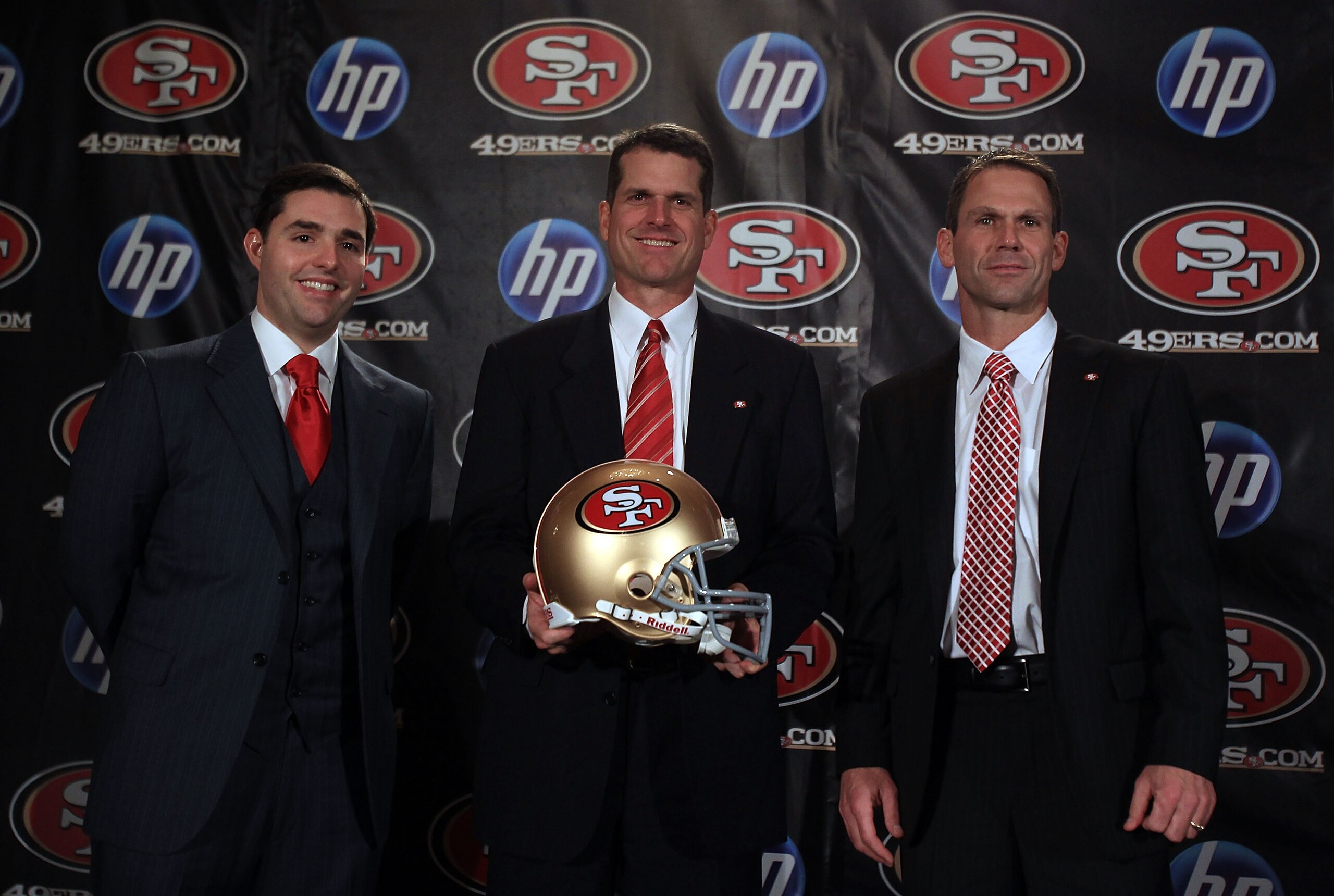 SAN FRANCISCO, CA - JANUARY 07:  Jim Harbaugh poses for a picture with President and CEO of the San Francisco 49ers, Jed York, (left) and general manager Trent Baalk following a press conference where Harbaugh was introduced as the new San Francisco 49ers