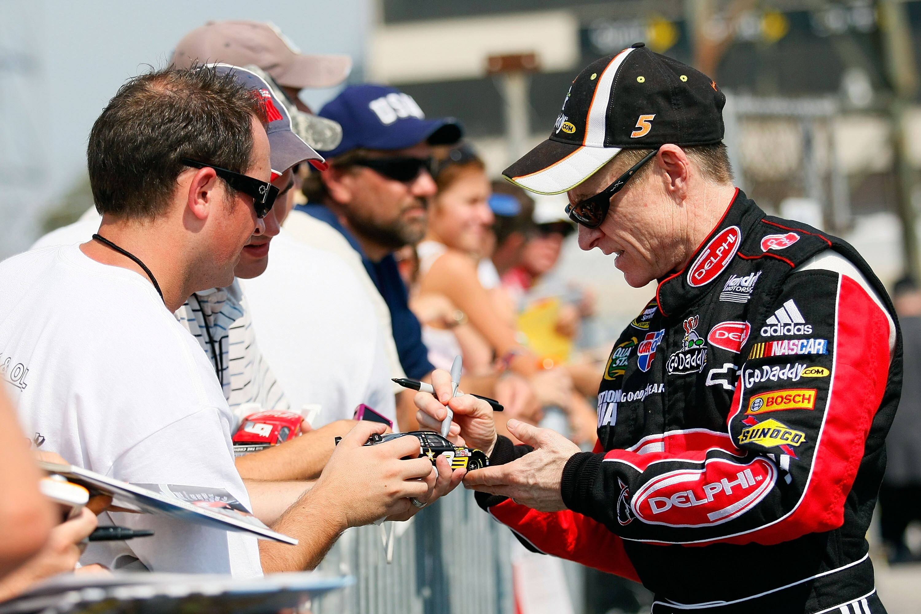 DOVER, DE - SEPTEMBER 24:  Mark Martin (R), driver of the #5 Delphi/GoDaddy.com Chevrolet, signs autographs for fans after practice for the NASCAR Sprint Cup Series AAA 400 at Dover International Speedway on September 24, 2010 in Dover, Delaware.  (Photo