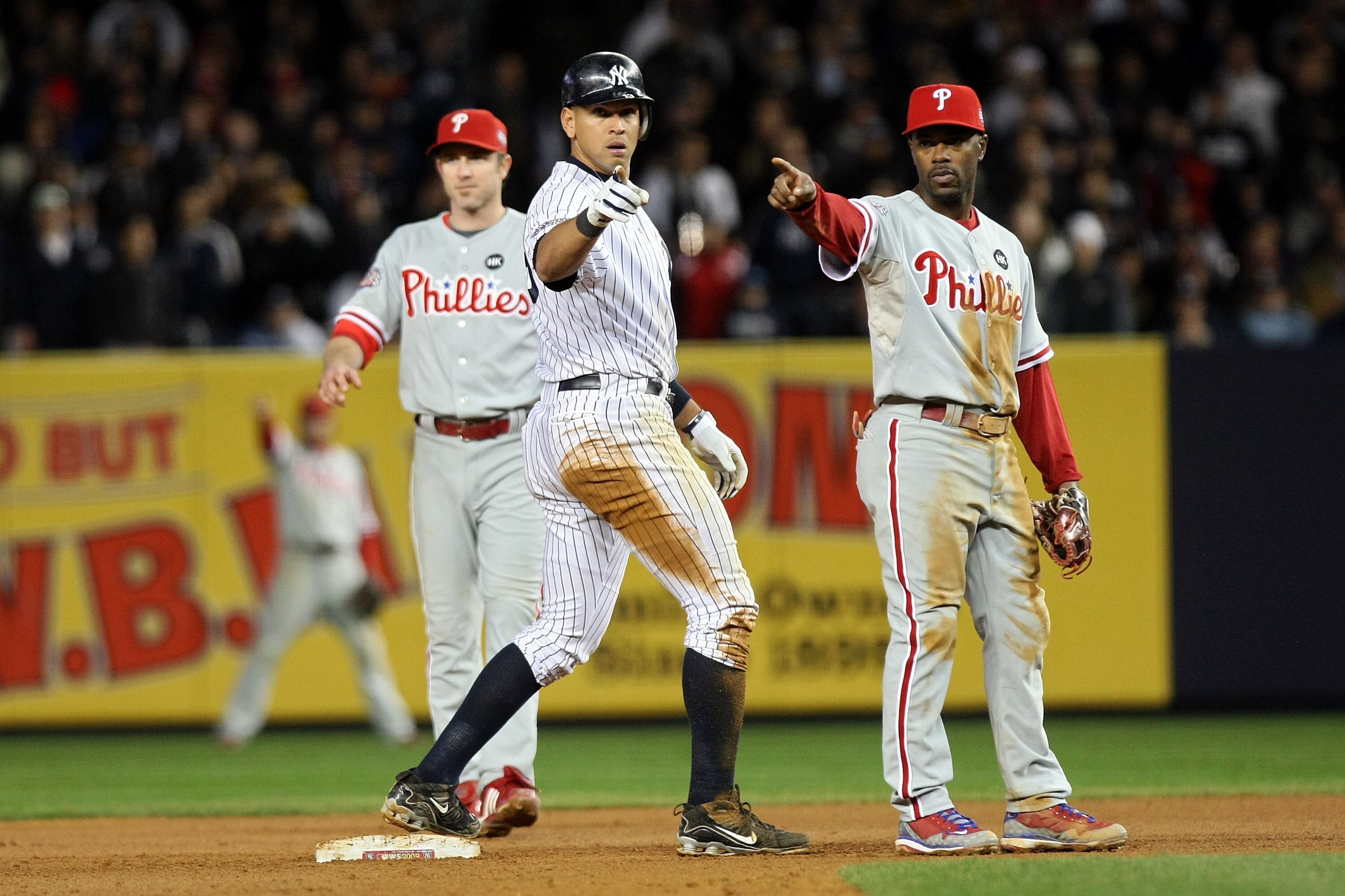 NEW YORK - NOVEMBER 04:  Alex Rodriguez #13 of the New York Yankees gestures after he stole second base in the bottom of the seventh inning against Chase Utley (L) #26 and Jimmy Rollins #11 of the Philadelphia Phillies look on in Game Six of the 2009 MLB