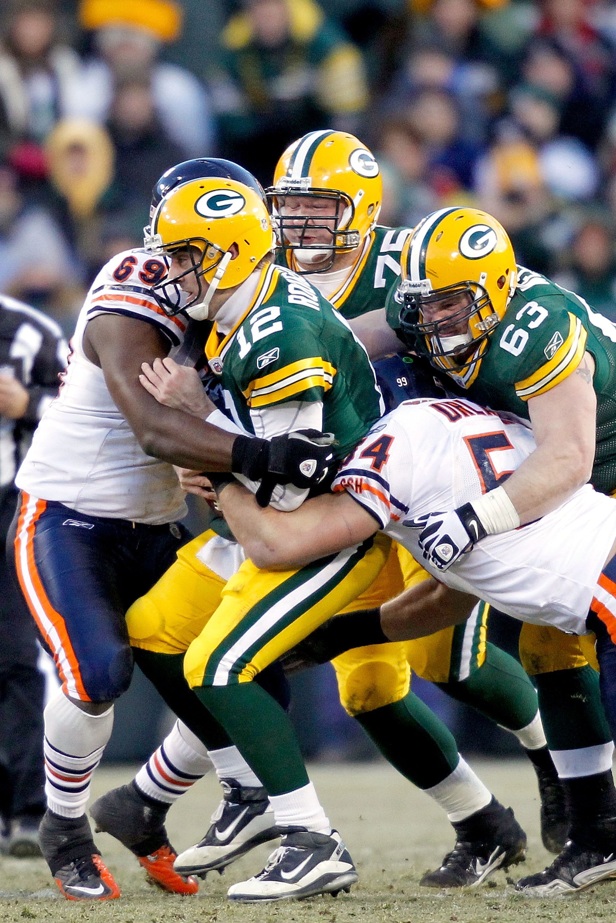 GREEN BAY, WI - JANUARY 02:  Quarterback Aaron Rodgers #12 of the Green Bay Packers is sacked by Henry Melton #69 and Brian Urlacher #54 of the Chicago Bears at Lambeau Field on January 2, 2011 in Green Bay, Wisconsin.  (Photo by Matthew Stockman/Getty Im