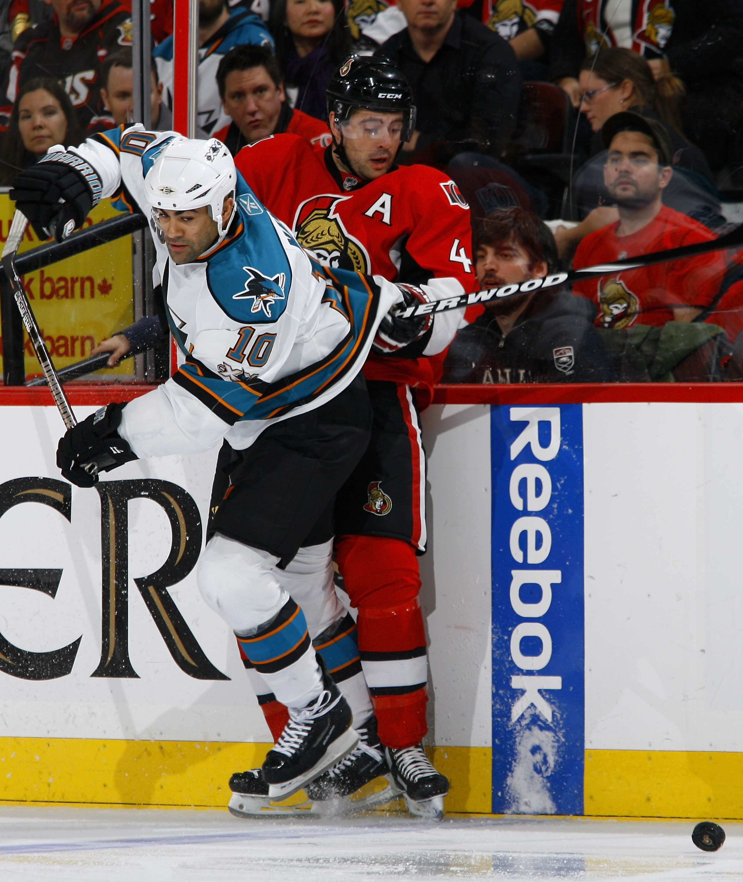 OTTAWA, ON - DECEMBER 02:  Chris Phillips #4 of the Ottawa Senators is knocked off the puck at the blueline by a hit from Jamal Mayers #10 of the San Jose Sharks in a game at Scotiabank Place on December 2, 2010 in Ottawa, Ontario, Canada.  (Photo by Phil