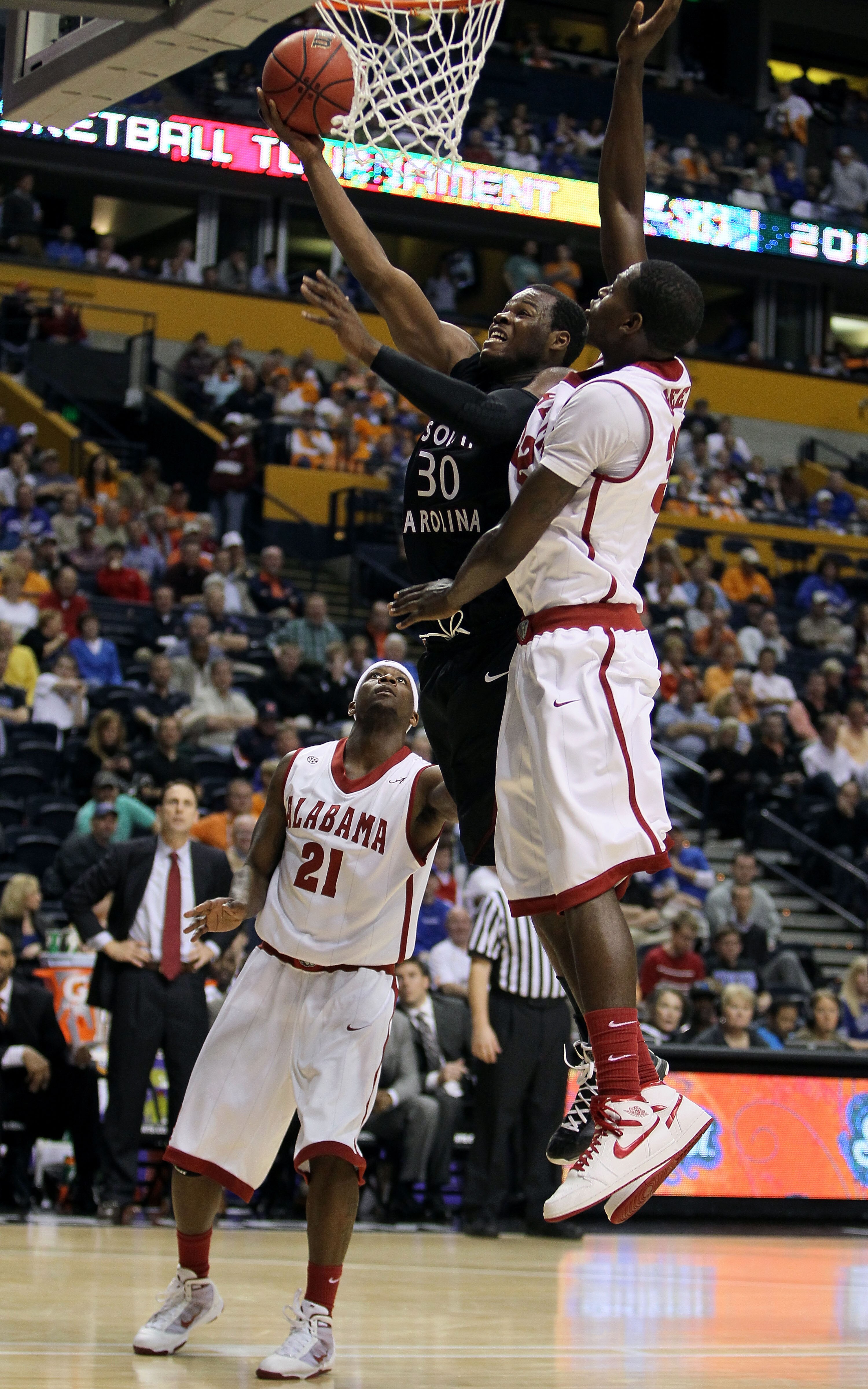 NASHVILLE, TN - MARCH 11:  Johndre Jefferson #30 of the South Carolina Gamecocks drives for a shot attempt against Jamychal Green #32 and Senario Hillman #21 of the Alabama Crimson Tide during the first round of the SEC Men's Basketball Tournament at the