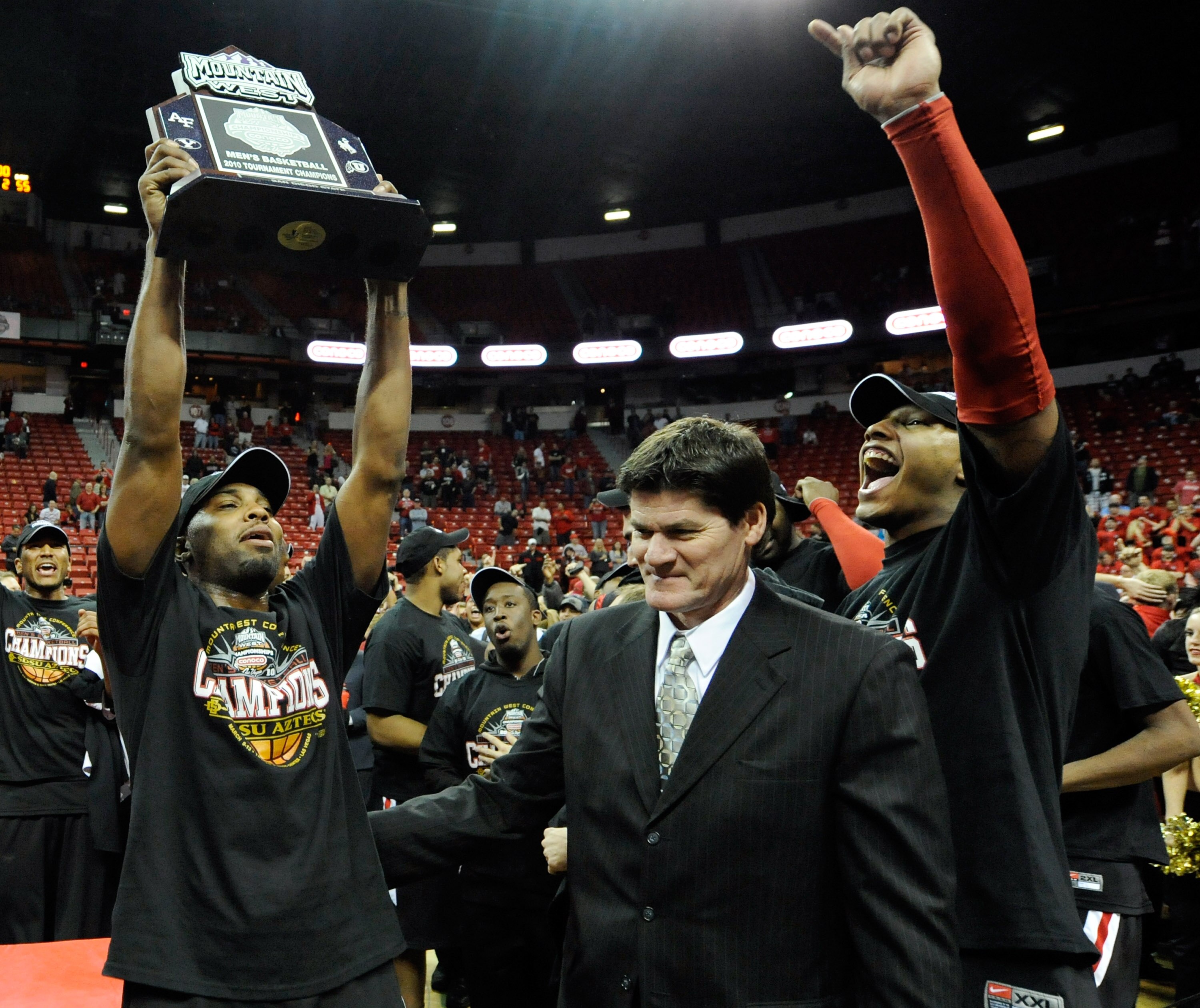 LAS VEGAS - MARCH 13:  Kelvin Davis (L) #40 and Billy White (R) #32 of the San Diego State Aztecs celebrate after receiving the trophy from Mountain West Conference Commissioner Craig Thompson (C) after beating the UNLV Rebels 55-45 in the championship ga