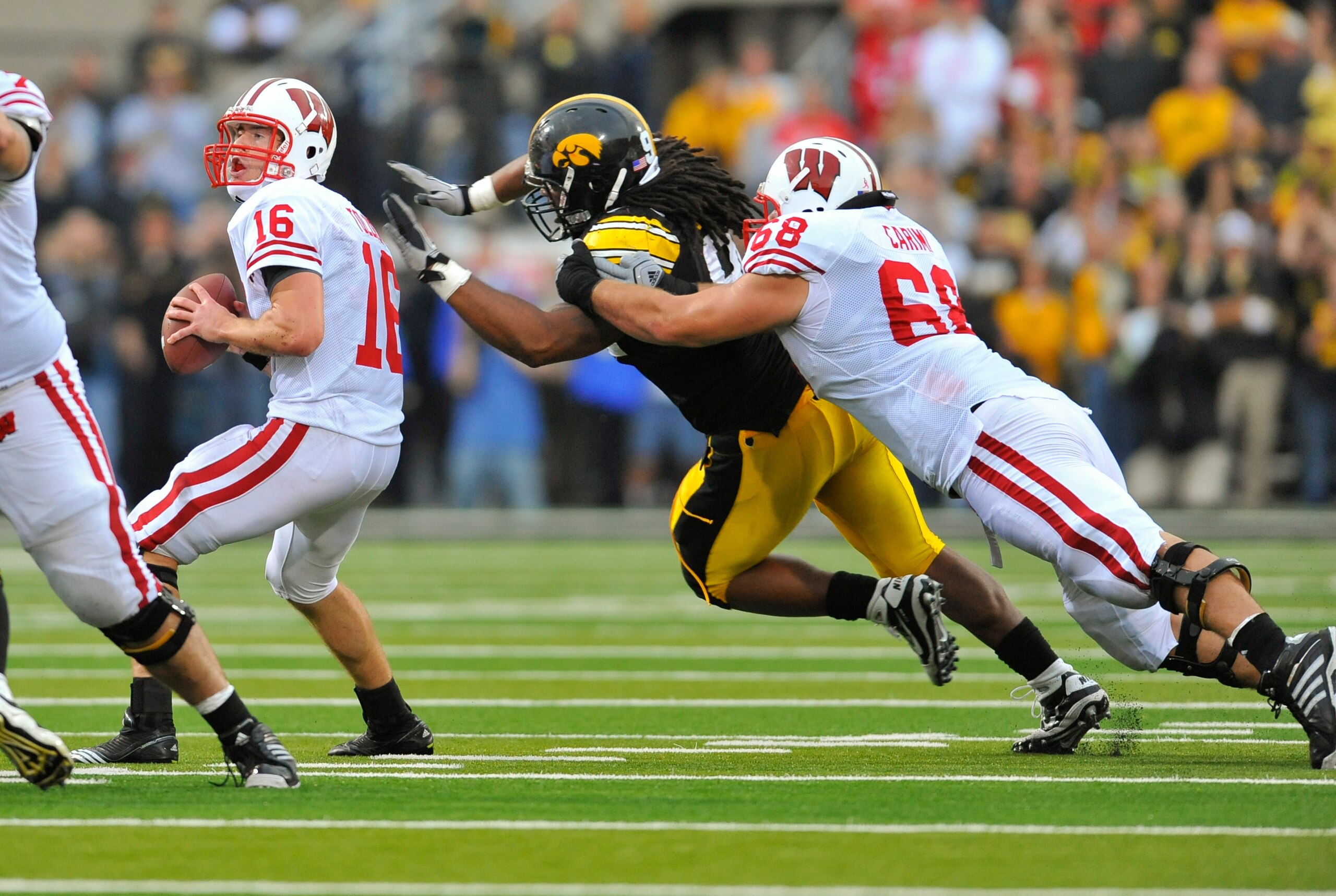 IOWA CITY, IA - OCTOBER 23- Quarterback Scott Tolzien #16 of the Wisconsin Badgers throws under pressure from Defensive lineman Adrian Clayborn #94 of the University of Iowa Hawkeyes as offensive lineman Gabe Carimi #68 defends during the first half of pl