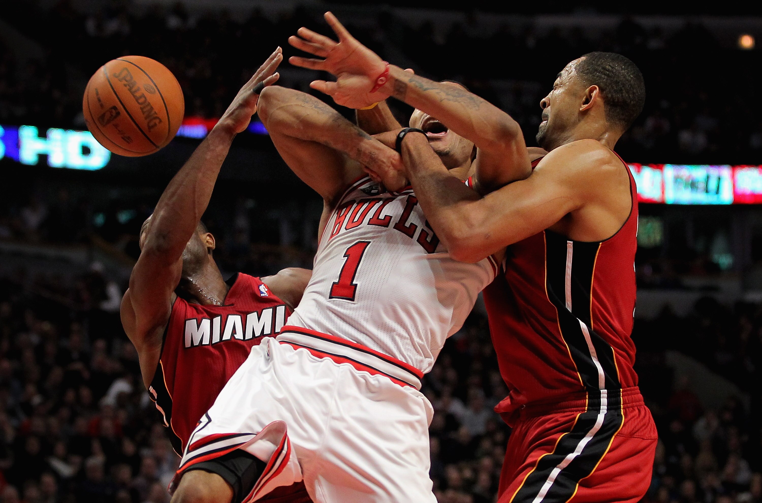 CHICAGO, IL - JANUARY 15:  Derrick Rose #1 of the Chicago Bulls looses control of the ball as he is fouled by Juwan Howard (R) #5 of the Miami Heat as Dwyane Wade (L) #3 of the Heat follows the action at the United Center on January 15, 2011 in Chicago, I