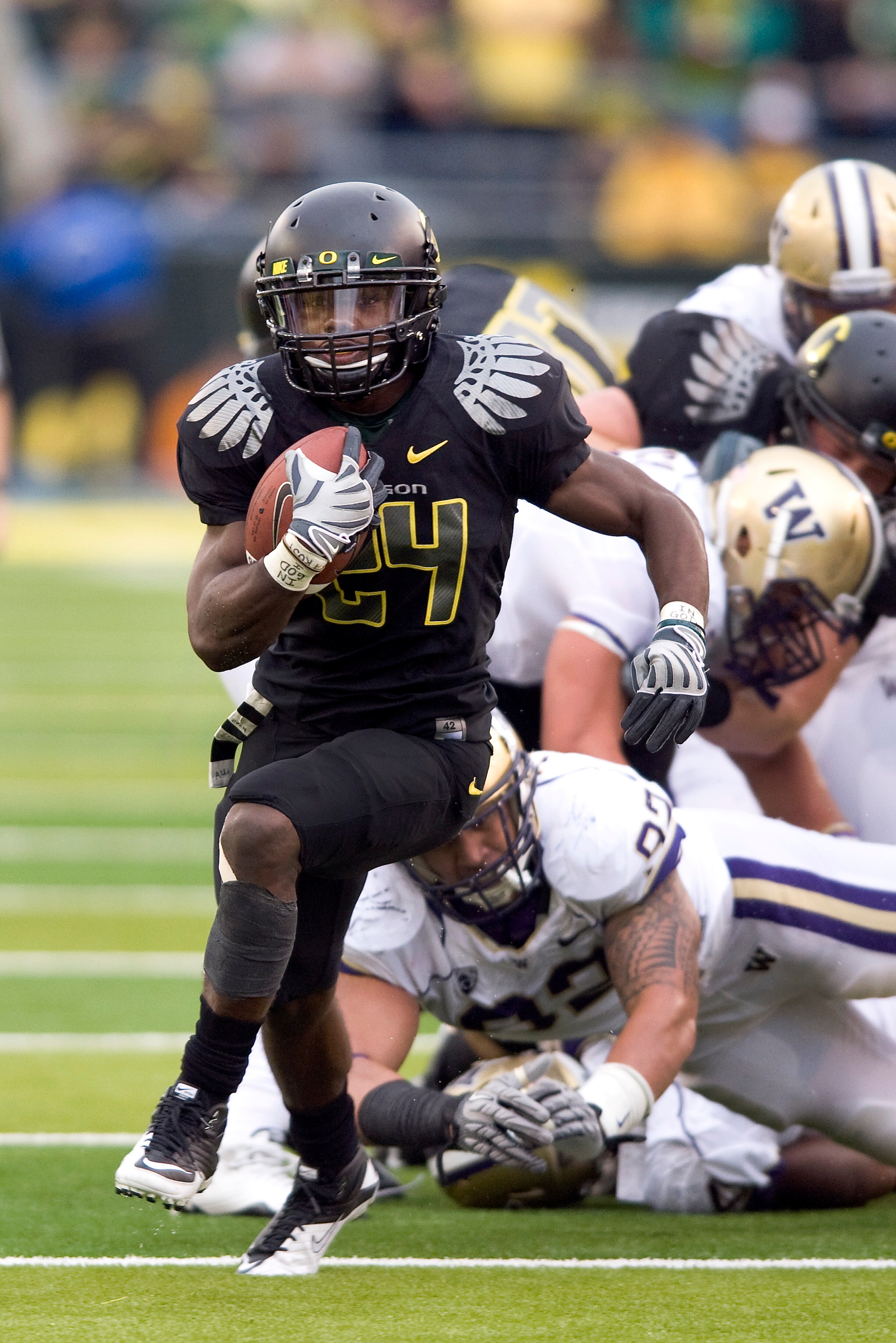 EUGENE, OR - NOVEMBER 6: Running back Kenjon Barner #24 of the Oregon Ducks leaves a pile of defenders as he runs with the ball in the fourth quarter of the game against the Washington Huskies at Autzen Stadium on November 6, 2010 in Eugene, Oregon. The D