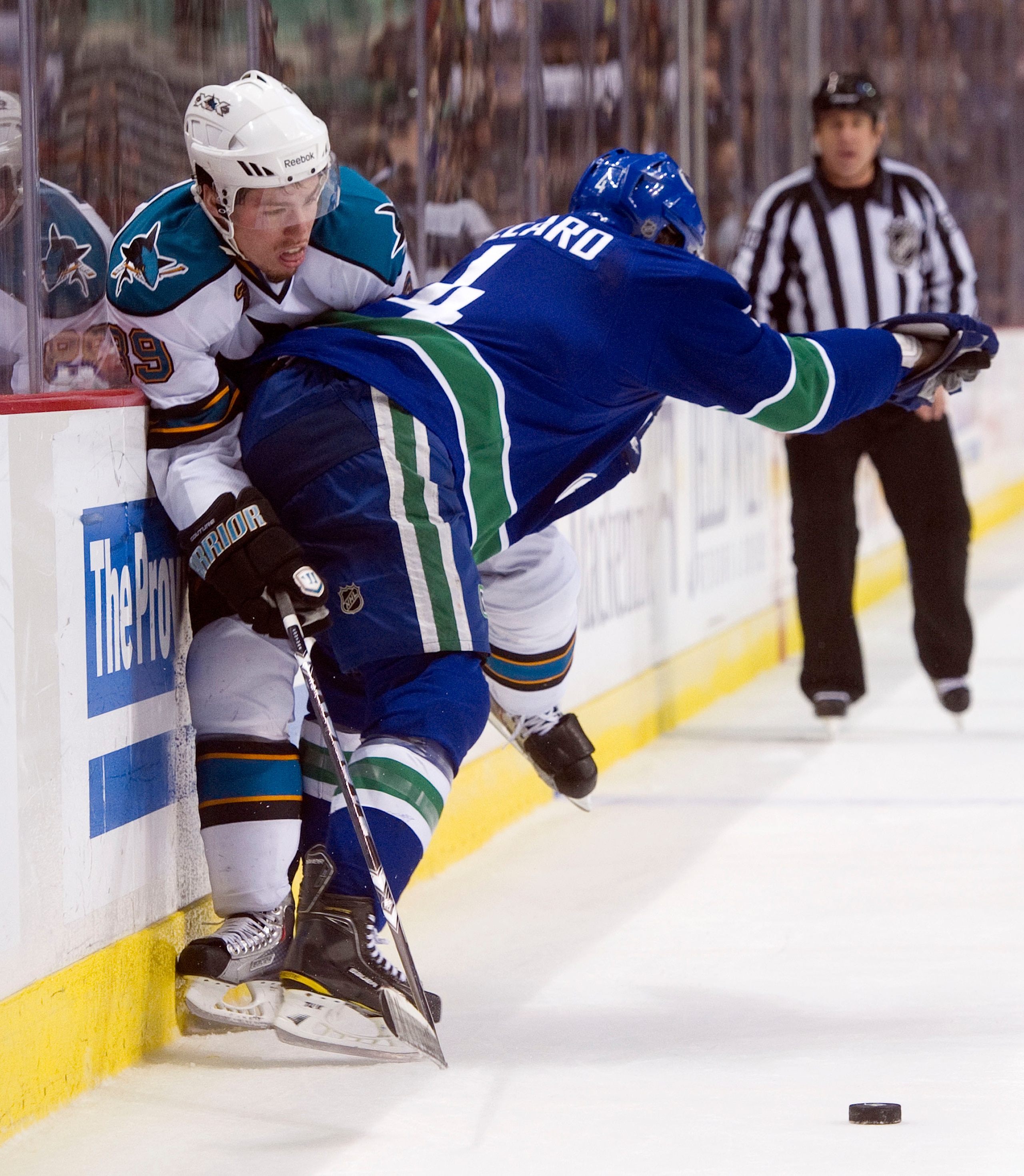 VANCOUVER, CANADA - JANUARY 20: Keith Ballard #4 of the Vancouver Canucks connects with a hip check on Logan Couture #39 of the San Jose Sharks during the third period in NHL action on January 20, 2011 at Rogers Arena in Vancouver, BC, Canada.  (Photo by
