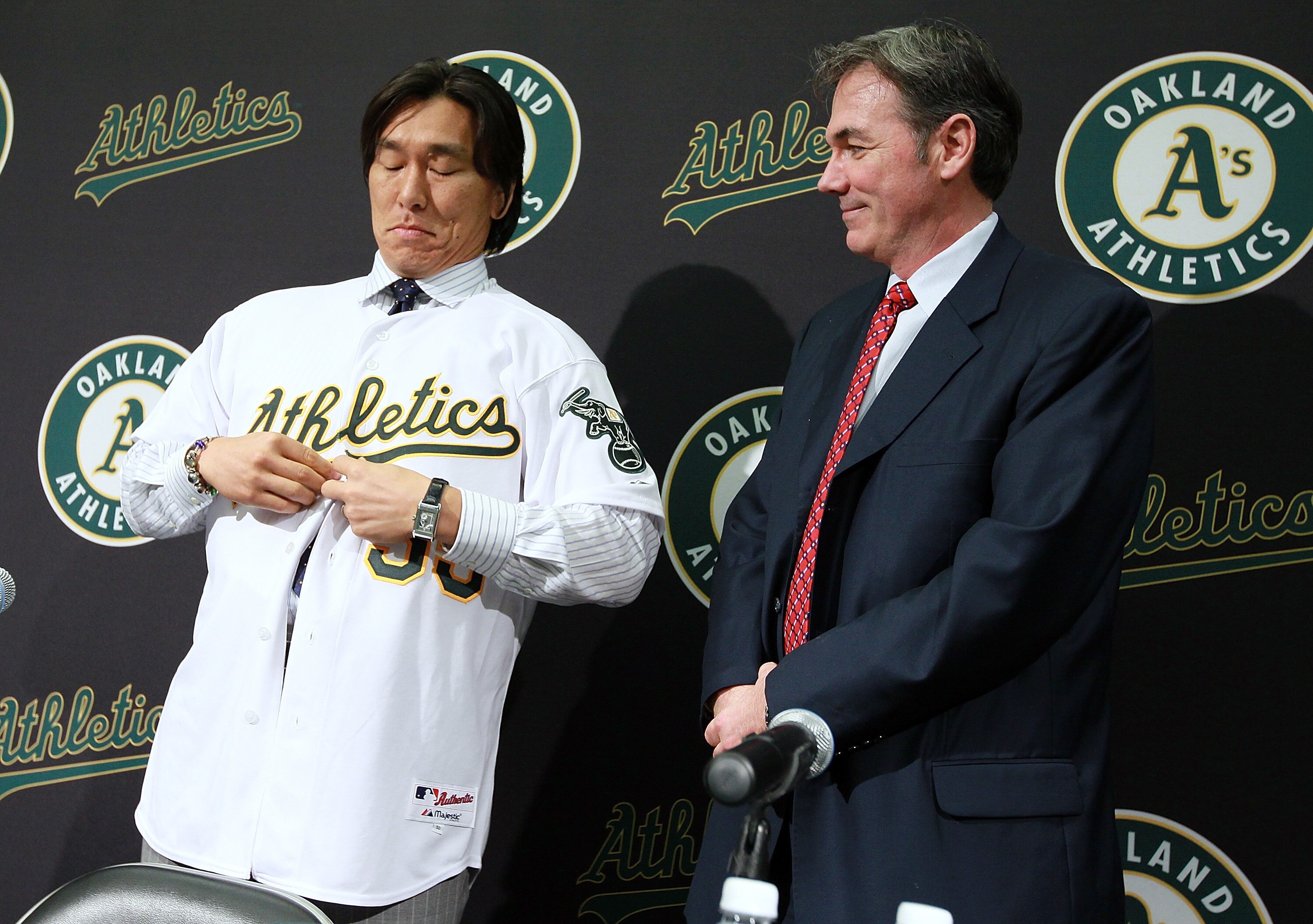 OAKLAND, CA - DECEMBER 14:  Oakland Athletics general manager Billy Beane (R) looks on as Hideki Matsui (R) buttons his new jersey during a press conference where he was introduced as the newest member of the Oakland Athletics at Oakland-Alameda County Co