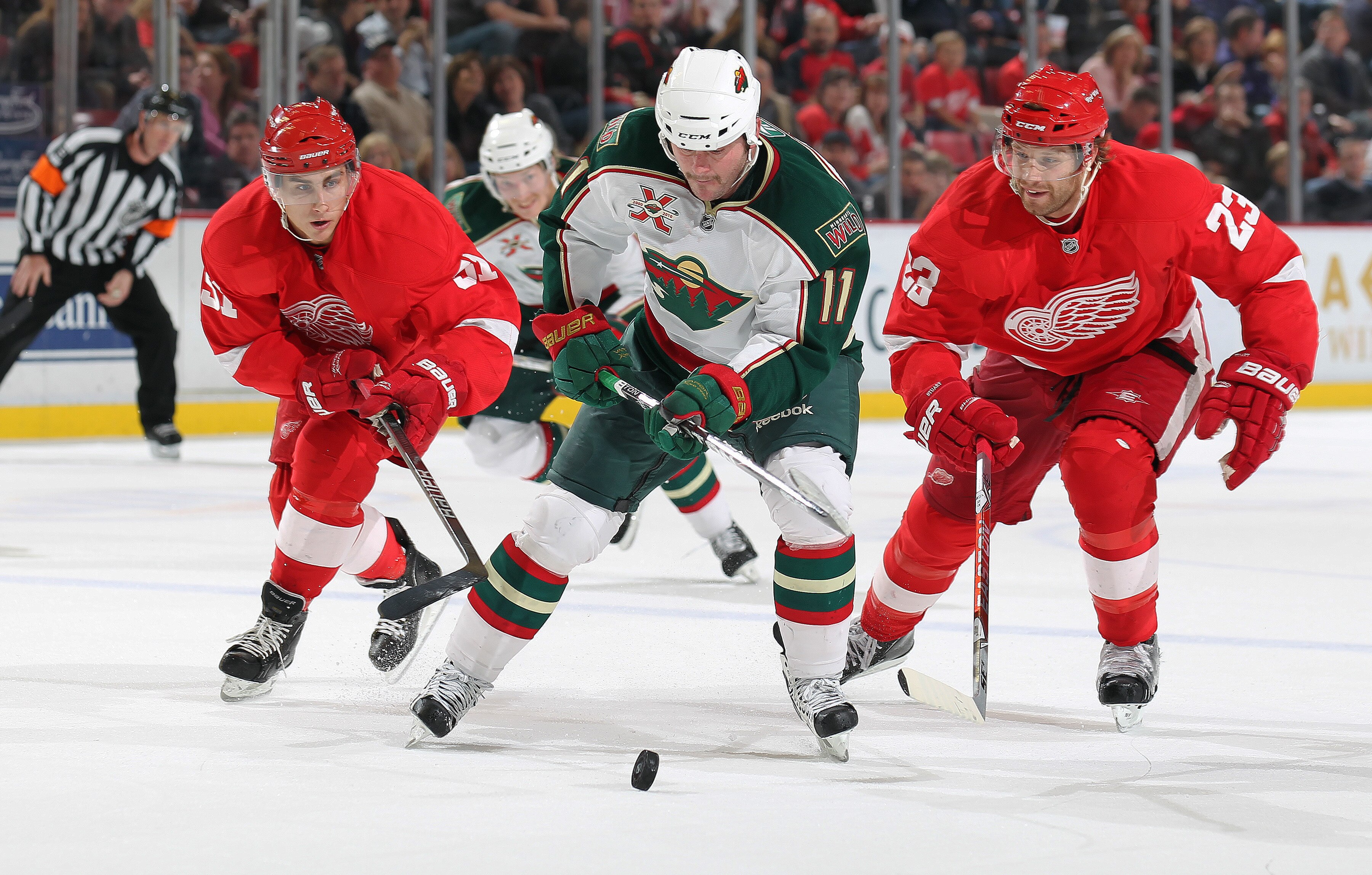 DETROIT, MI - NOVEMBER 19:  John Madden #11 of the Minnesota Wild skates in on a break while being checked by Valtteri Filppula #51 and Brad Stuart #23 of the Detroit Red Wings in a game on November 19, 2010 at the Joe Louis Arena in Detroit, Michigan. Th