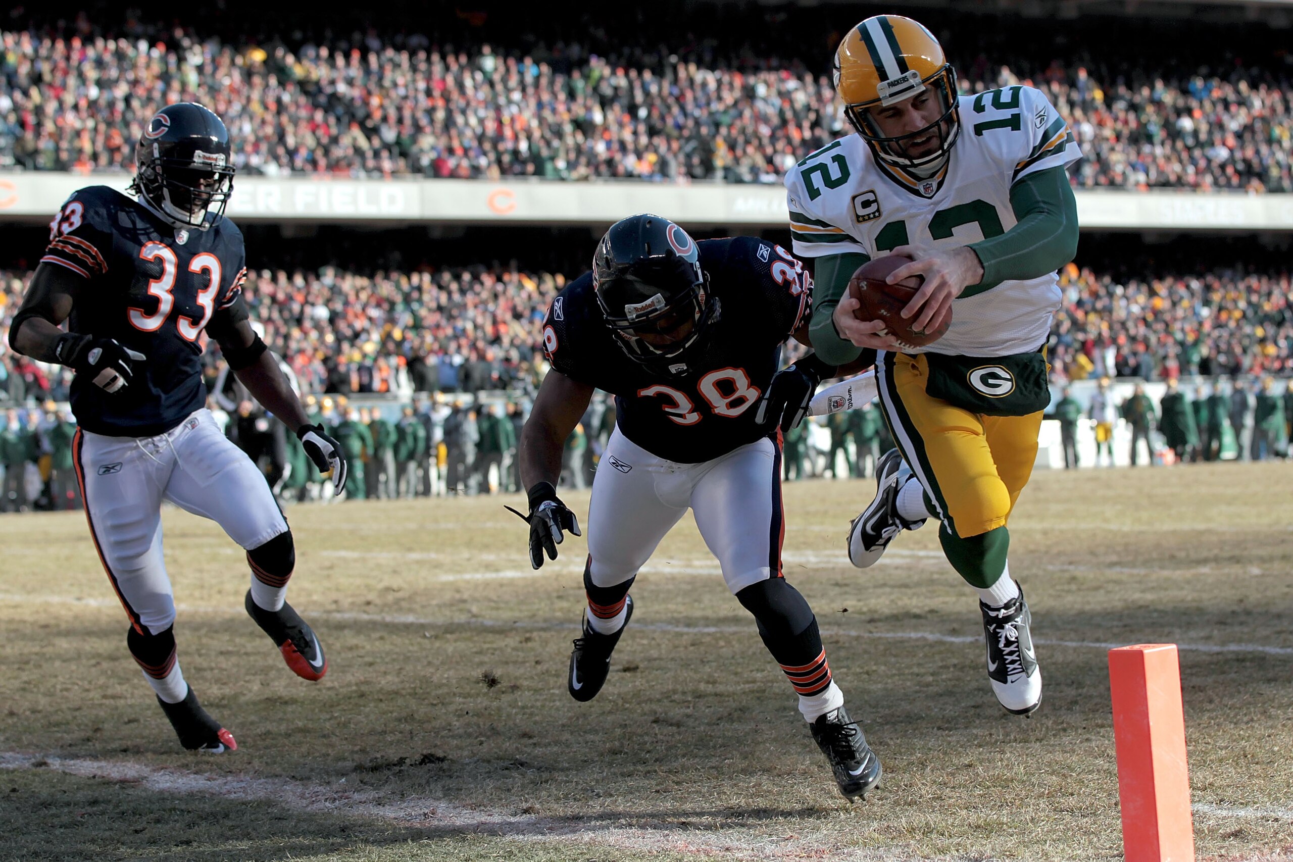 CHICAGO, IL - JANUARY 23:  Quarterback Aaron Rodgers #12 of the Green Bay Packers dives into the corner of the endzone for a one-yard touchdown run against Danieal Manning #38 of the Chicago Bears in the first quarter of the NFC Championship Game at Soldi