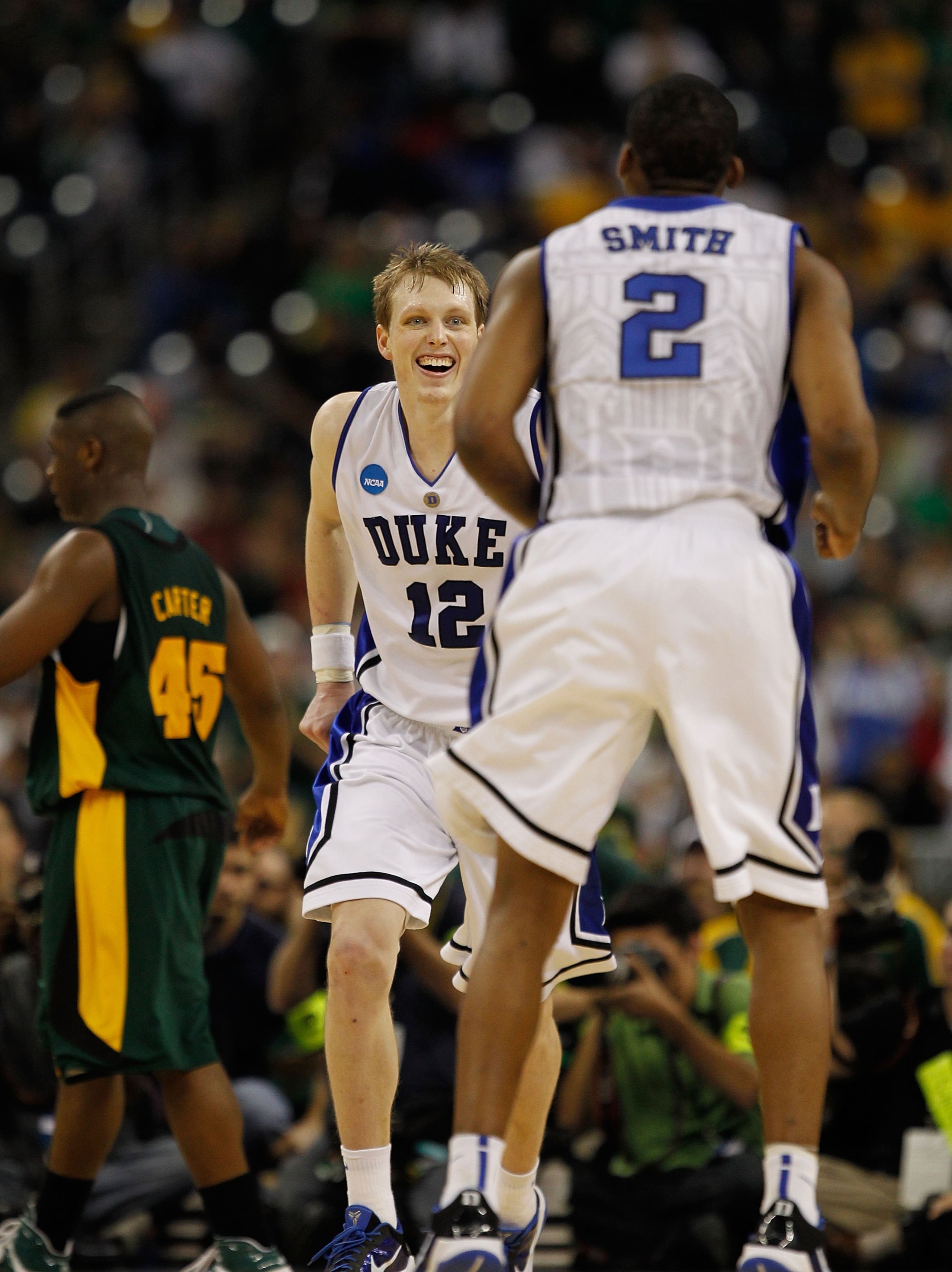 HOUSTON - MARCH 28: Kyle Singler #12 of the Duke Dlue Devils smiles as he runs to greet teammate Nolan Smith #5 near the end of a game against the Baylor Bears during the south regional final of the 2010 NCAA men's basketball tournament at Reliant Stadium