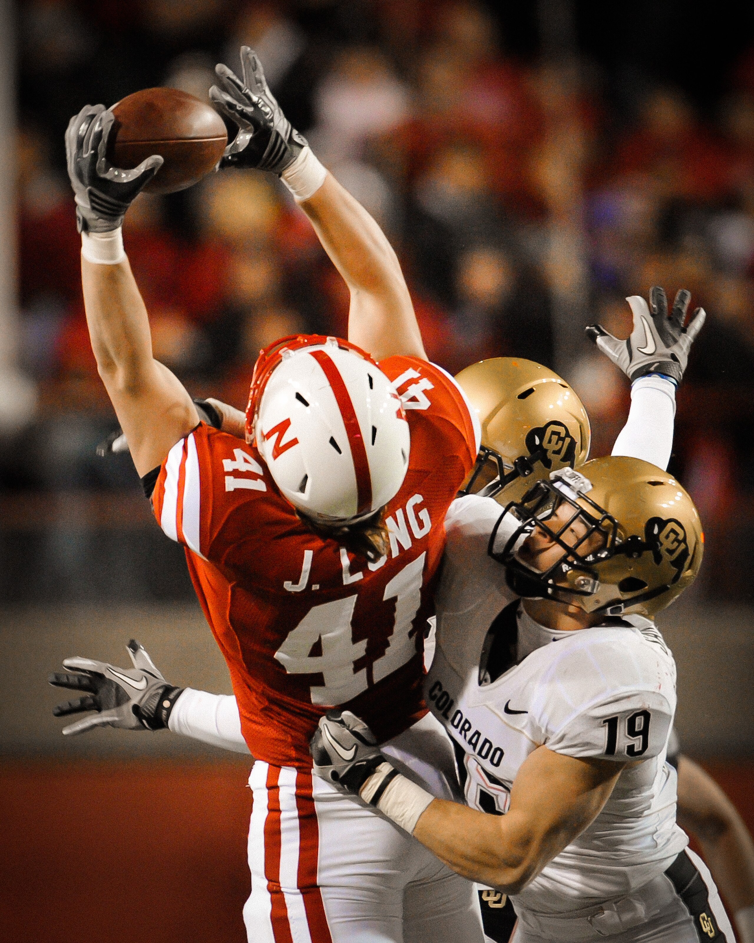 LINCOLN, NE - NOVEMBER 26: Jake Long #41 of the Nebraska Cornhuskers catches a pass over Travis Sandersfeld #19 and Jalil Brown #23 of the Colorado Buffaloes during the second half of their game at Memorial Stadium on November 26, 2010 in Lincoln, Nebrask