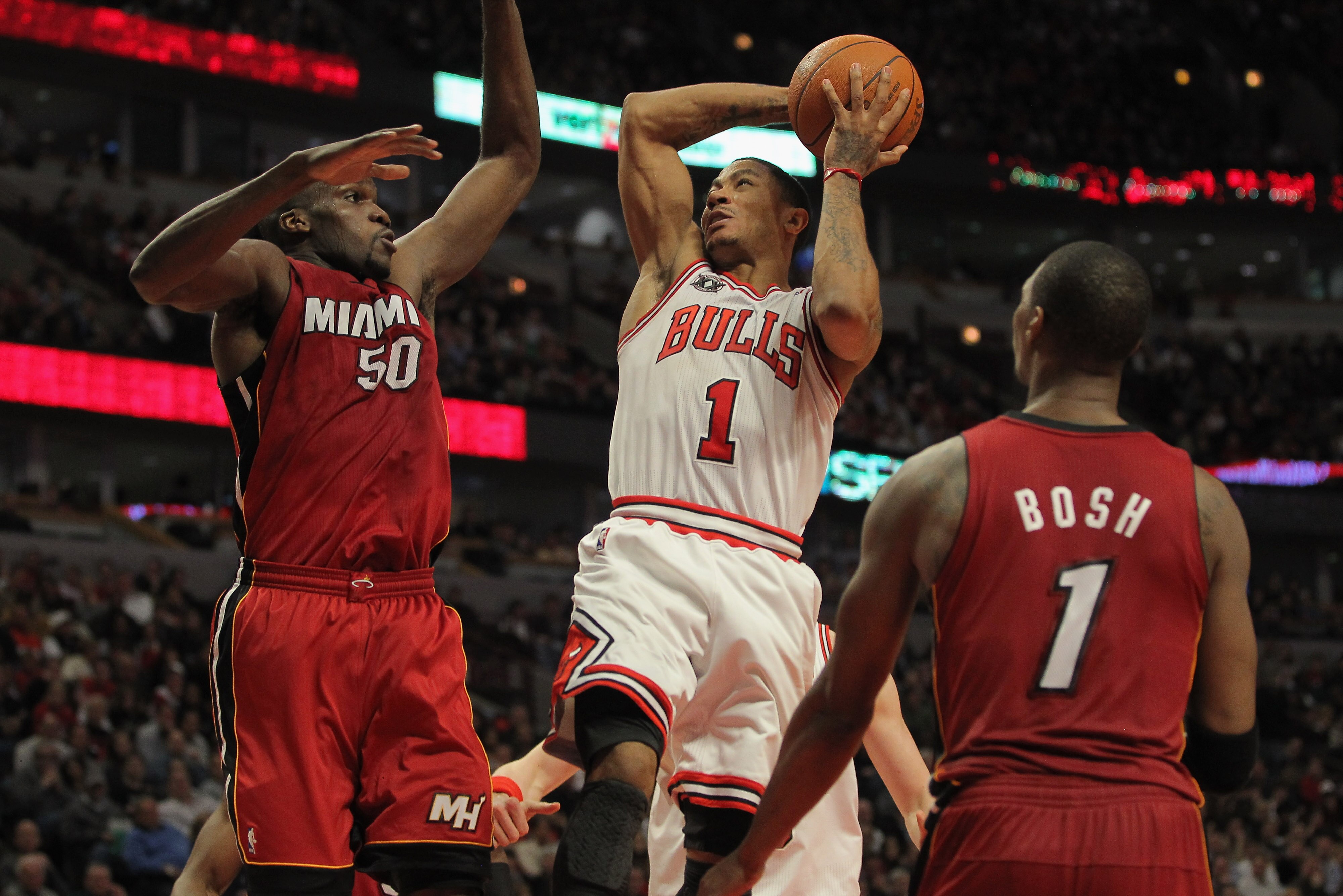 CHICAGO, IL - JANUARY 15:  Derrick Rose #1 of the Chicago Bulls gets off a shot as he is fouled by Joel Anthony #50 of the Miami Heat while Chris Bosh #1 of the Heat follows the action at the United Center on January 15, 2011 in Chicago, Illinois. NOTE TO