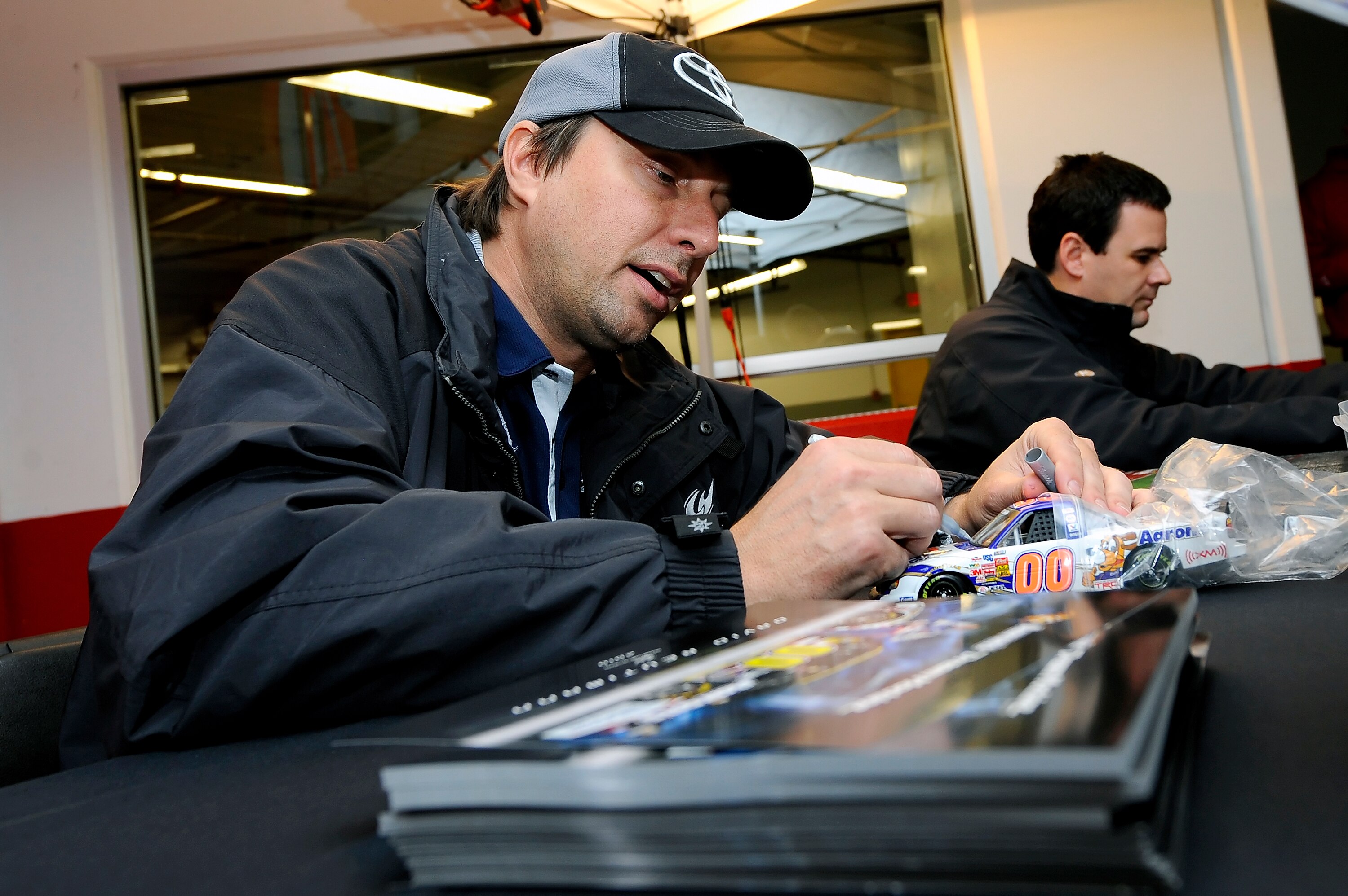DAYTONA BEACH, FL - JANUARY 21:  David Reutimann, driver of the #00 Aaron's Toyota, signs autographs for some race fans after testing at Daytona International Speedway on January 21, 2011 in Daytona Beach, Florida.  (Photo by Jared C. Tilton/Getty Images