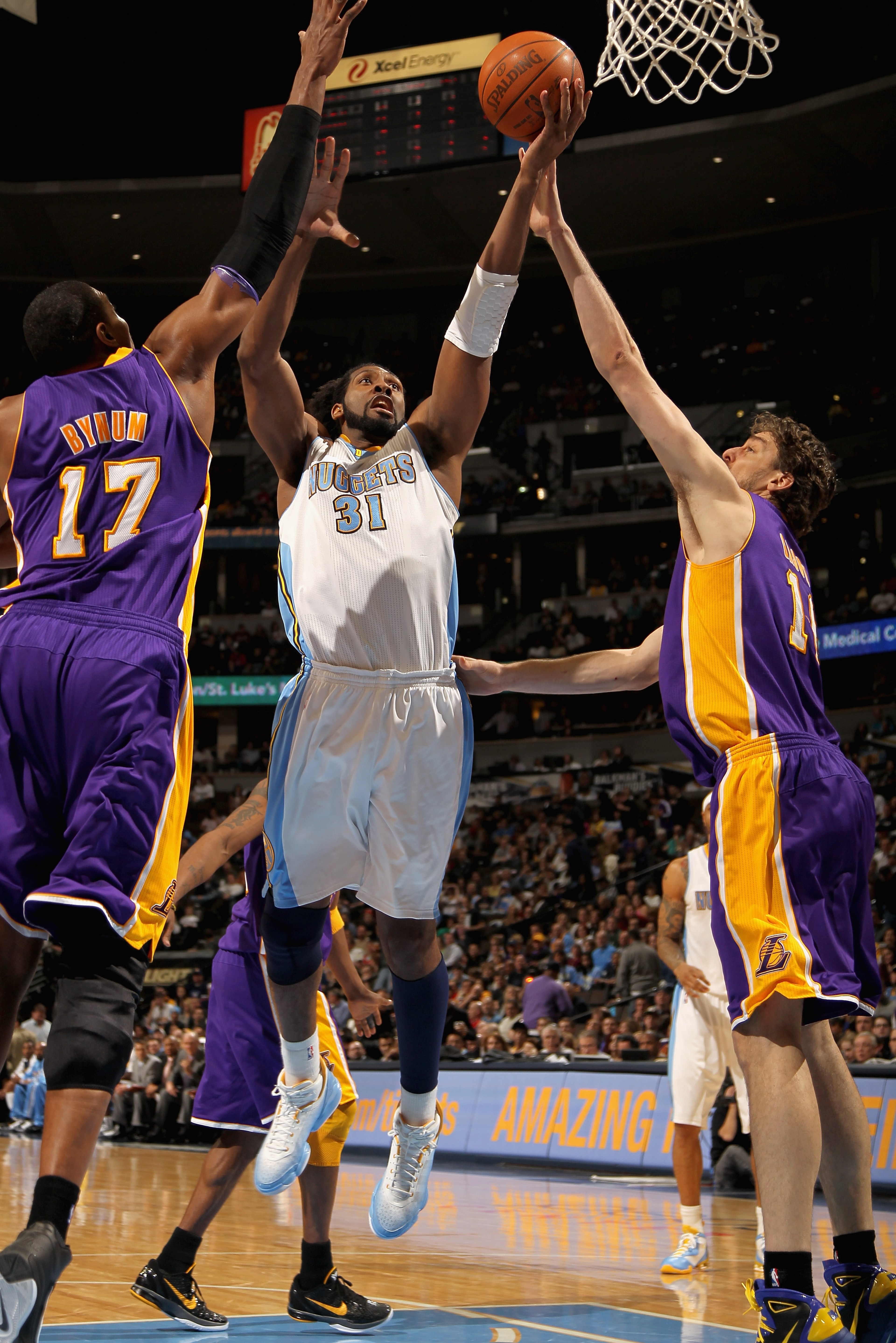 DENVER, CO - JANUARY 21:  Nene #31 of the Denver Nuggets puts up a shot between Andrew Bynum #17 and Pau Gasol #16 of the Los Angeles Lakers at the Pepsi Center on January 21, 2011 in Denver, Colorado. The Lakers defeated the Nuggets 107-97. NOTE TO USER: