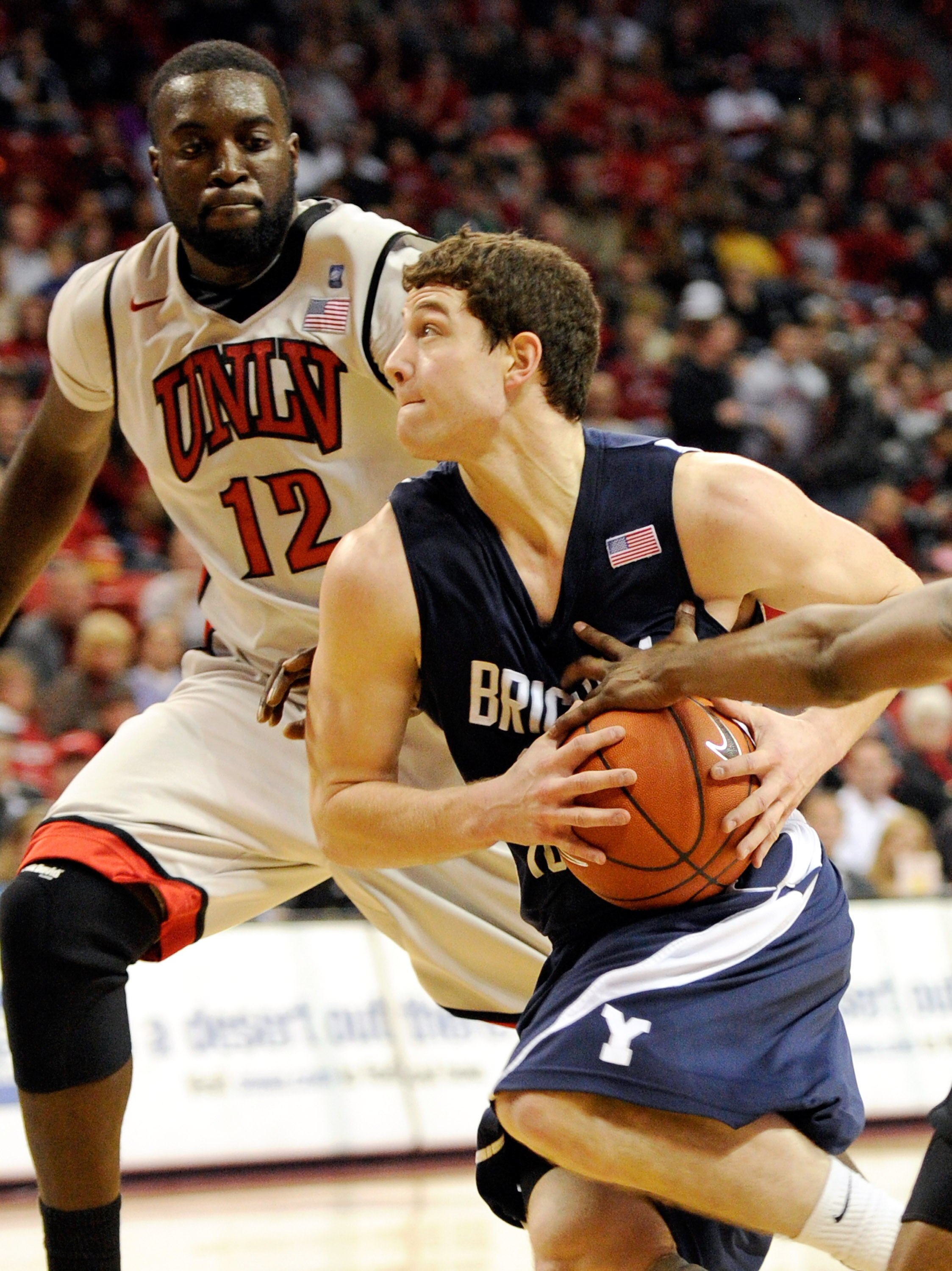 LAS VEGAS, NV - JANUARY 05:  Jimmer Fredette #32 of the Brigham Young University Cougars drives against Brice Massamba #12 of the UNLV Rebels during their game at the Thomas & Mack Center January 5, 2011 in Las Vegas, Nevada. BYU won 89-77.  (Photo by Eth