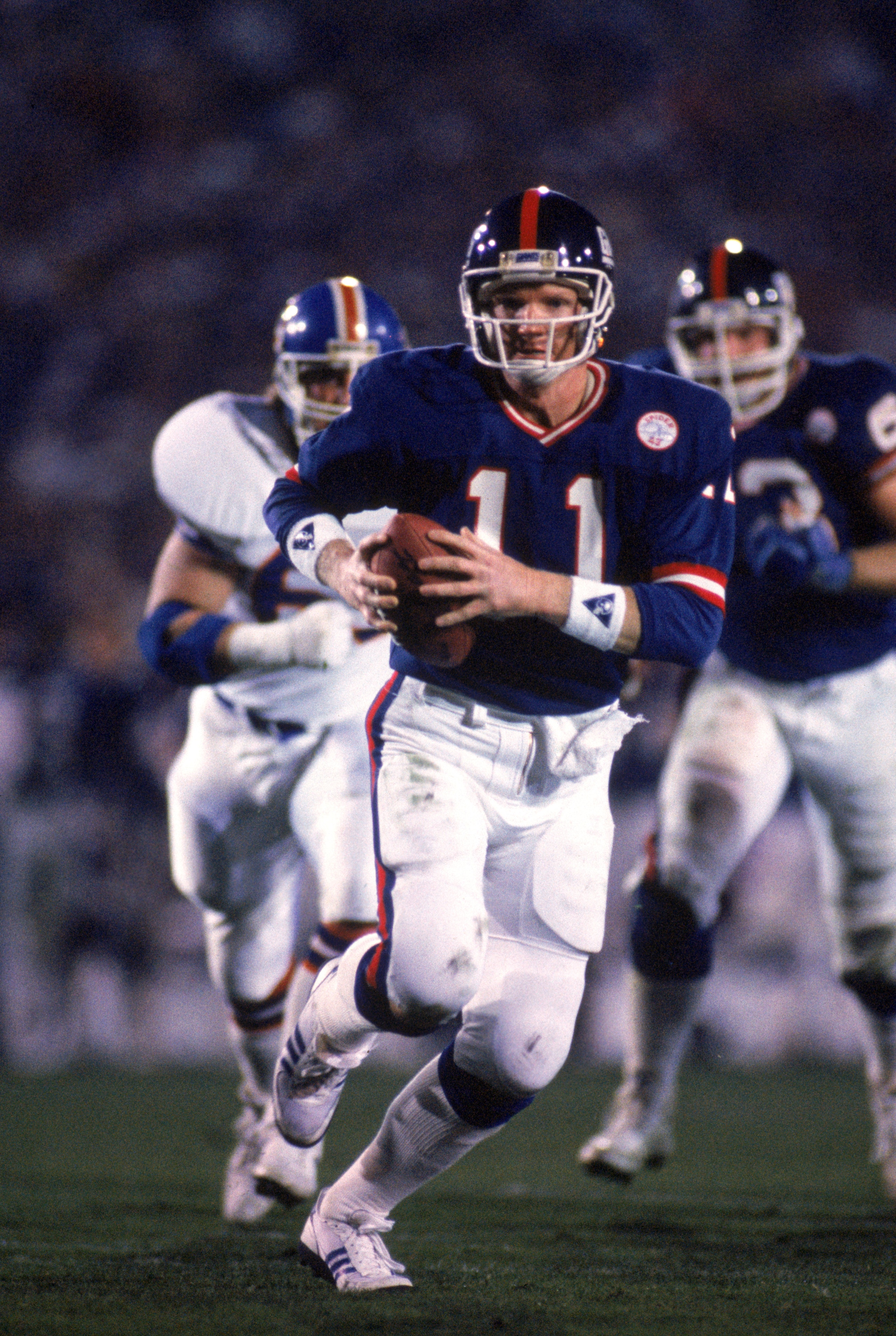 PASADENA, CA - JANUARY 25:  Quarterback Phil Simms #11 of the New York Giants runs with the ball against the Denver Broncos during Super Bowl XXI at the Rose Bowl on January 25, 1987 in Pasadena, California. The Giants defeated the Broncos 39-20. (Photo b