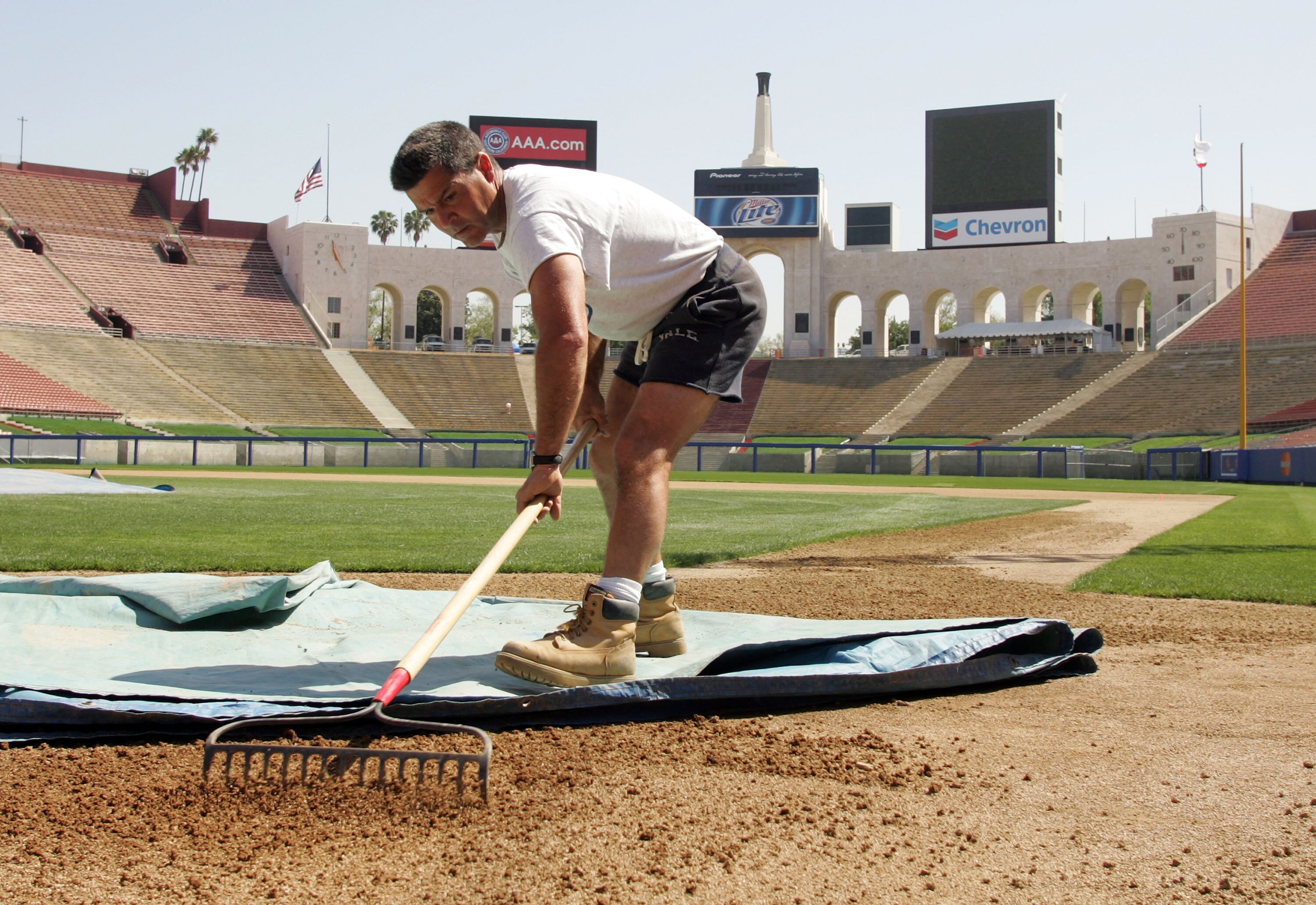 LOS ANGELES, CA - MARCH 27:  Grounds crew member Mark D'Antonio rakes the dirt at home plate at the Memorial Coliseum March 27, 2008 in Los Angeles, California. The exhibition game on March 29 marks the return of the Dodgers to their original Los Angeles