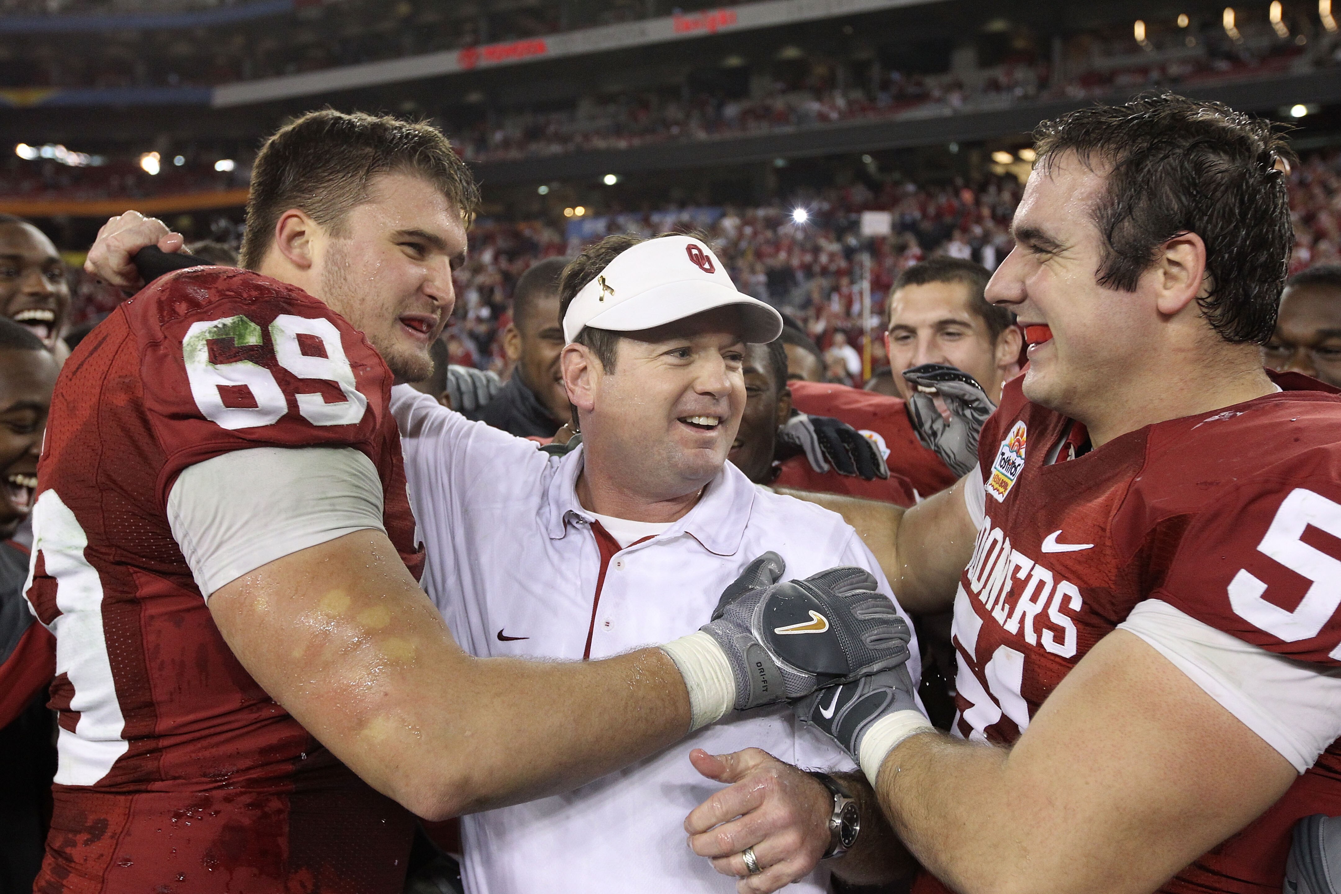GLENDALE, AZ - JANUARY 01:  Head coach Bob Stoops is hugged by Eric Mensik #69 and Brian Lepak #51 late in the fourth quarter before the Sooners 48-20 victory against the Connecticut Huskies during the Tostitos Fiesta Bowl at the Universtity of Phoenix St