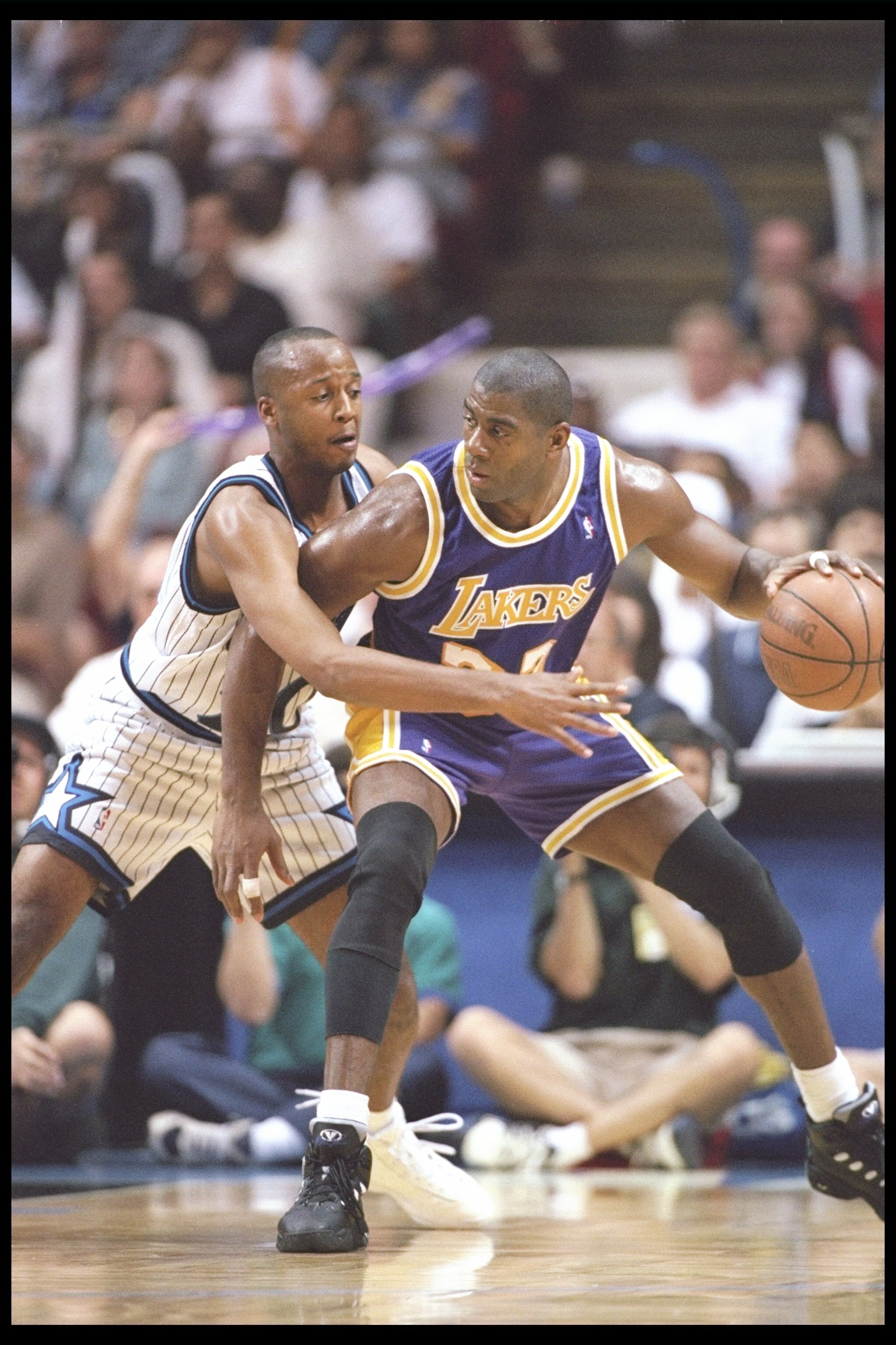 26 Mar 1996: Guard Magic Johnson of the Los Angeles Lakers tries to break free of guard Brian Shaw of the Orlando Magic during a game at the Orlando Arena in Orlando, Florida. The Lakers won the game 113-91.