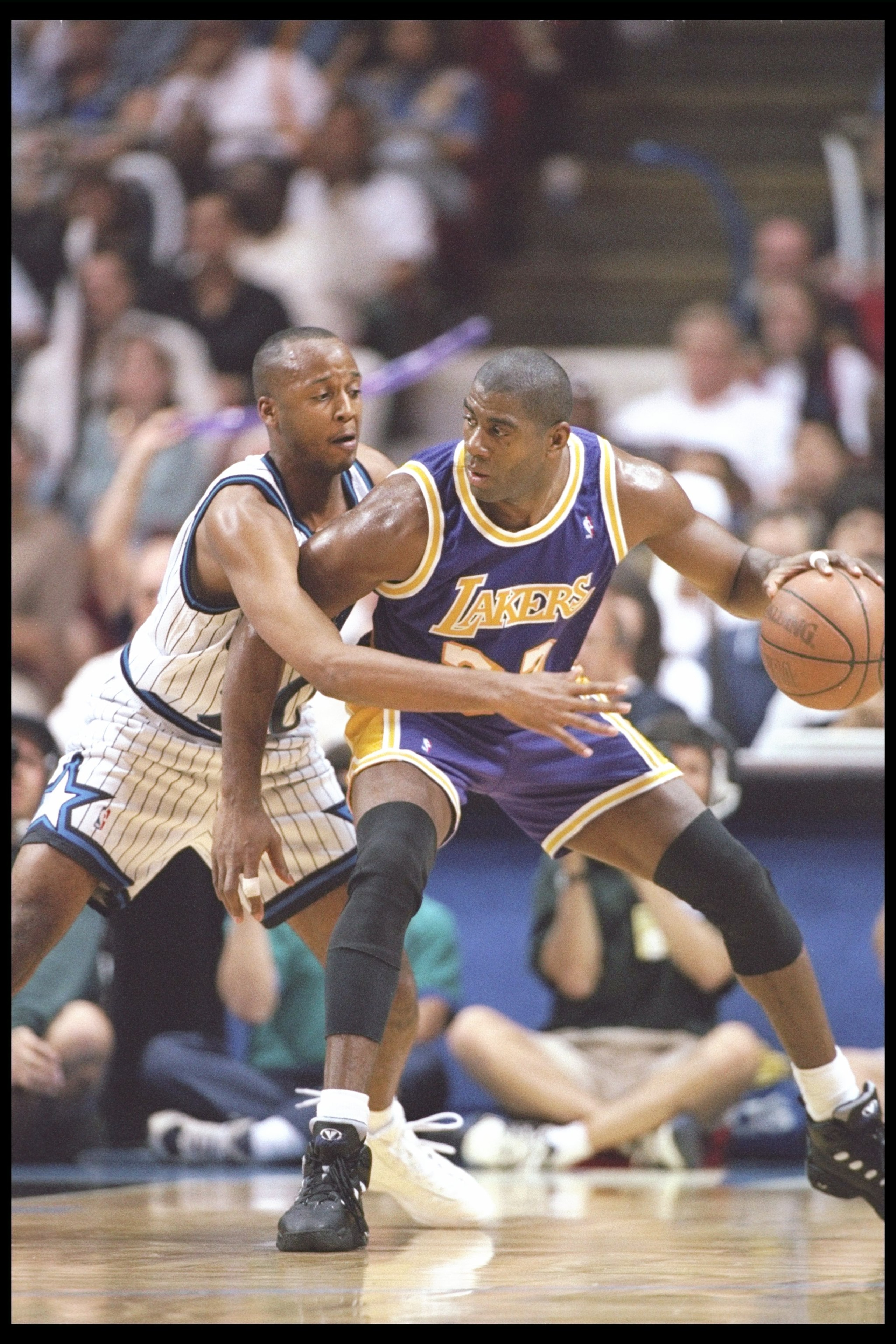 26 Mar 1996: Guard Magic Johnson of the Los Angeles Lakers tries to break free of guard Brian Shaw of the Orlando Magic during a game at the Orlando Arena in Orlando, Florida. The Lakers won the game 113-91.