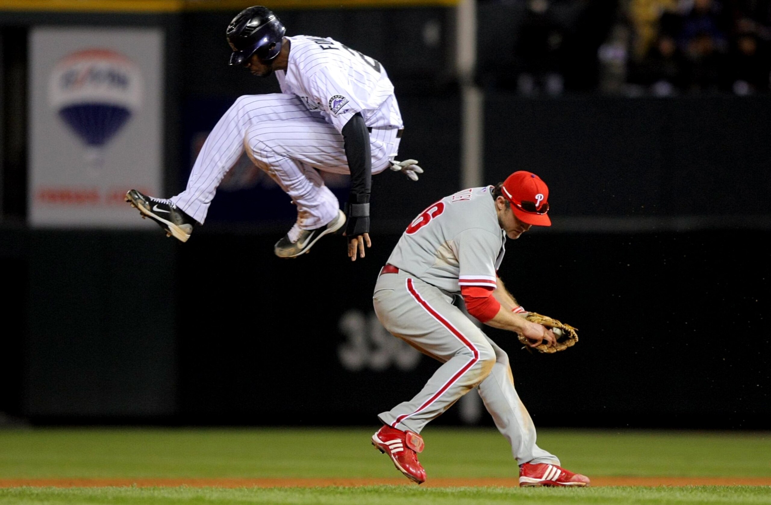 DENVER - OCTOBER 12: Dexter Fowler #24 of the Colorado Rockies hurdles safely over Chase Utley #26 the Philadelphia Phillies in Game Four of the NLDS during the 2009 MLB Playoffs at Coors Field on October 12, 2009 in Denver, Colorado. (Photo by Doug Pen DENVER - OCTOBER 12: Dexter Fowler #24 of the Colorado Rockies hurdles safely over Chase Utley #26 the Philadelphia Phillies in Game Four of the NLDS during the 2009 MLB Playoffs at Coors Field on October 12, 2009 in Denver, Colorado. (Photo by Doug Pen