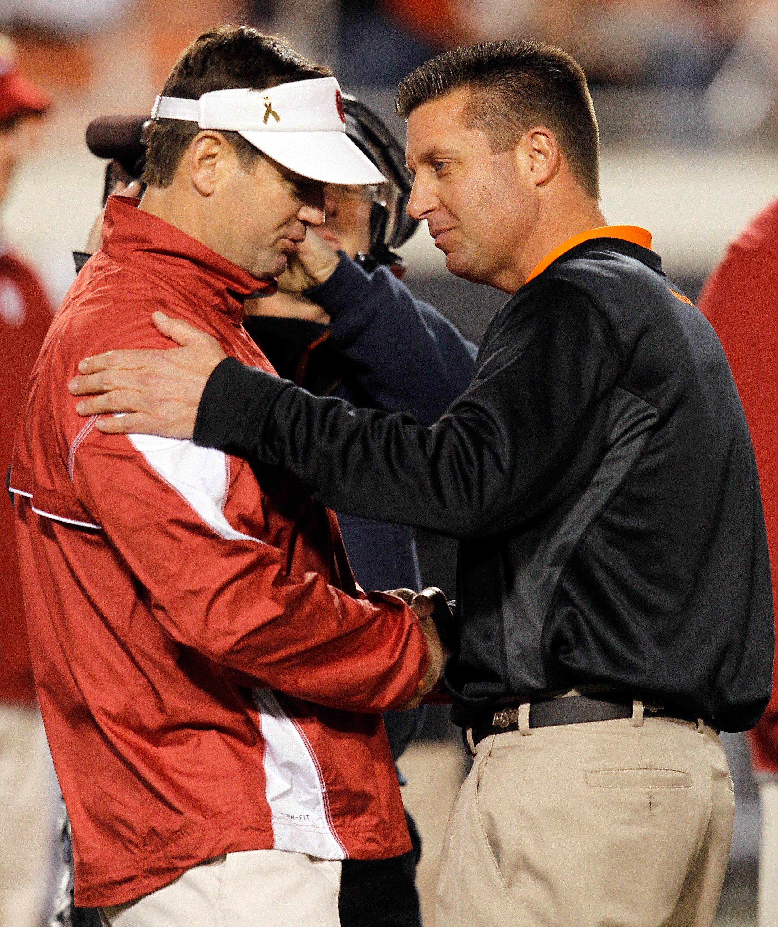STILLWATER, OK - NOVEMBER 27:  Head coach Bob Stoops (L) of the Oklahoma Sooners talks with head coach Mike Gundy (R) of the Oklahoma State Cowboys at Boone Pickens Stadium on November 27, 2010 in Stillwater, Oklahoma.  (Photo by Tom Pennington/Getty Imag