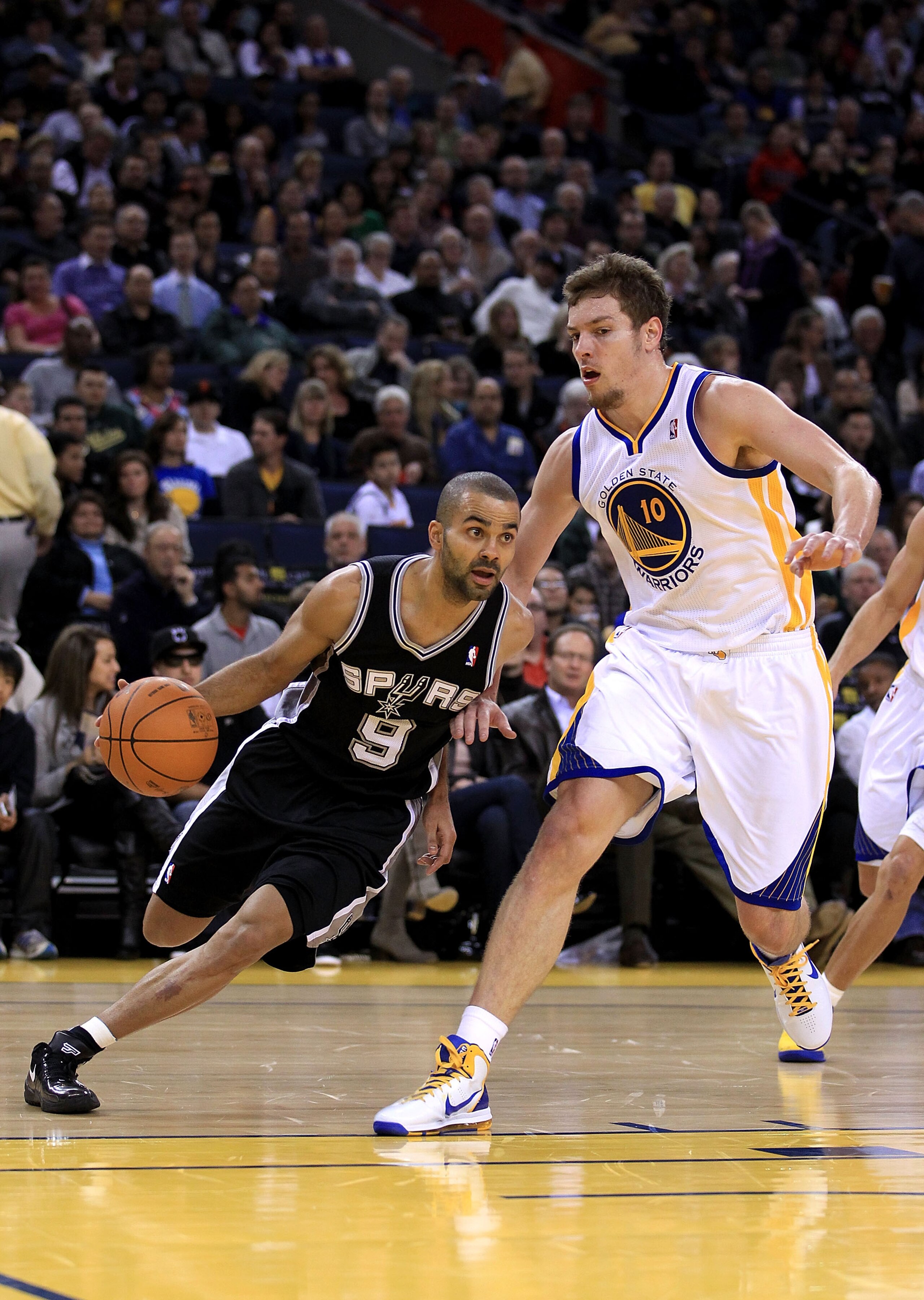 OAKLAND, CA - JANUARY 24:  Tony Parker #9 of the San Antonio Spurs drives on David Lee #10 of the Golden State Warriors at Oracle Arena on January 24, 2011 in Oakland, California.  NOTE TO USER: User expressly acknowledges and agrees that, by downloading