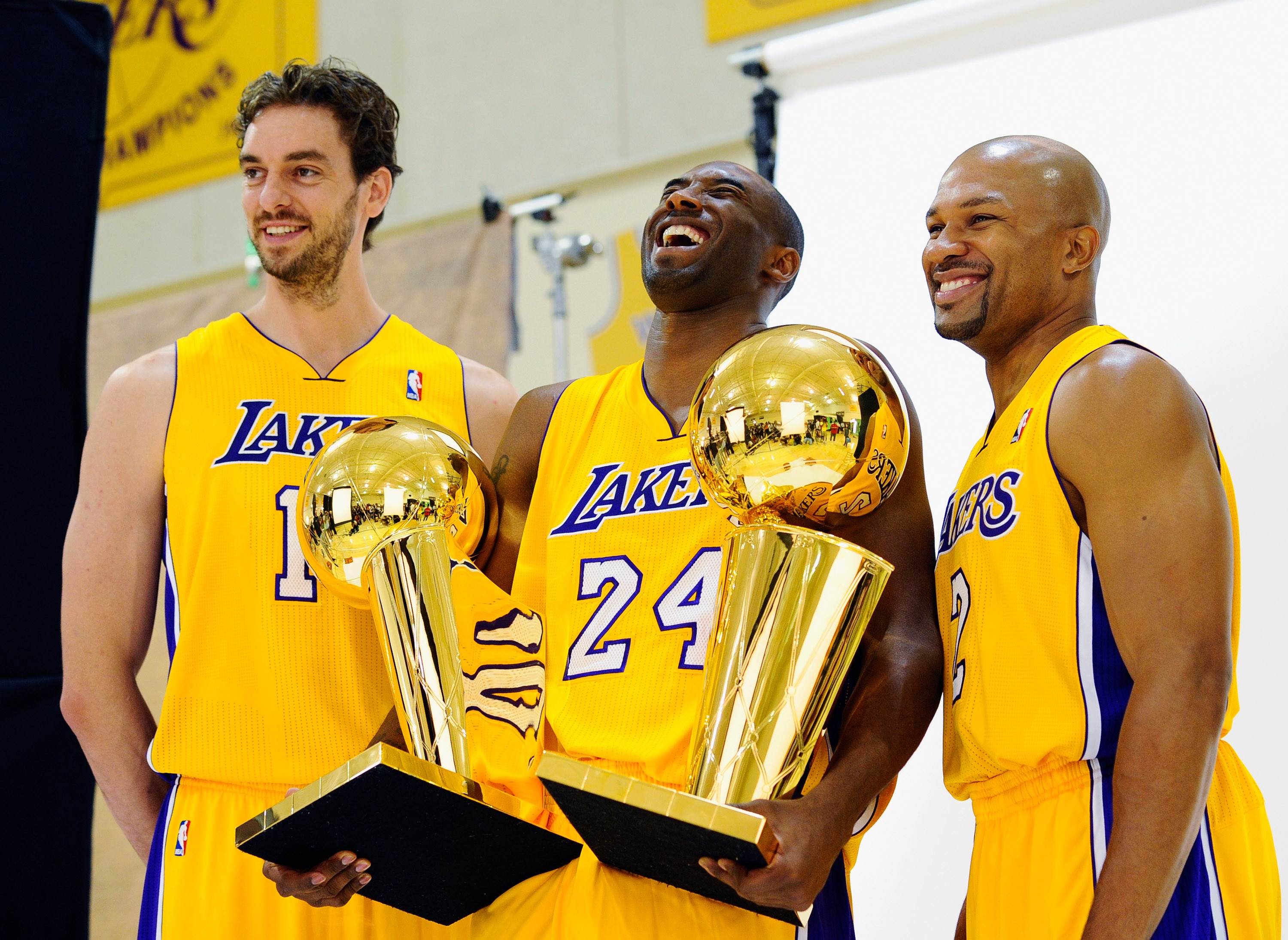 EL SEGUNDO, CA - SEPTEMBER 25:  Kobe Bryant #24  of the Los Angeles Lakers laughs as he holds two NBA Finals Larry O'Brien Championship Trophy's as he poses for a photograph with teammates Pau Gasol #16 and Derek Fisher #2 during Media Day at the Toyota C