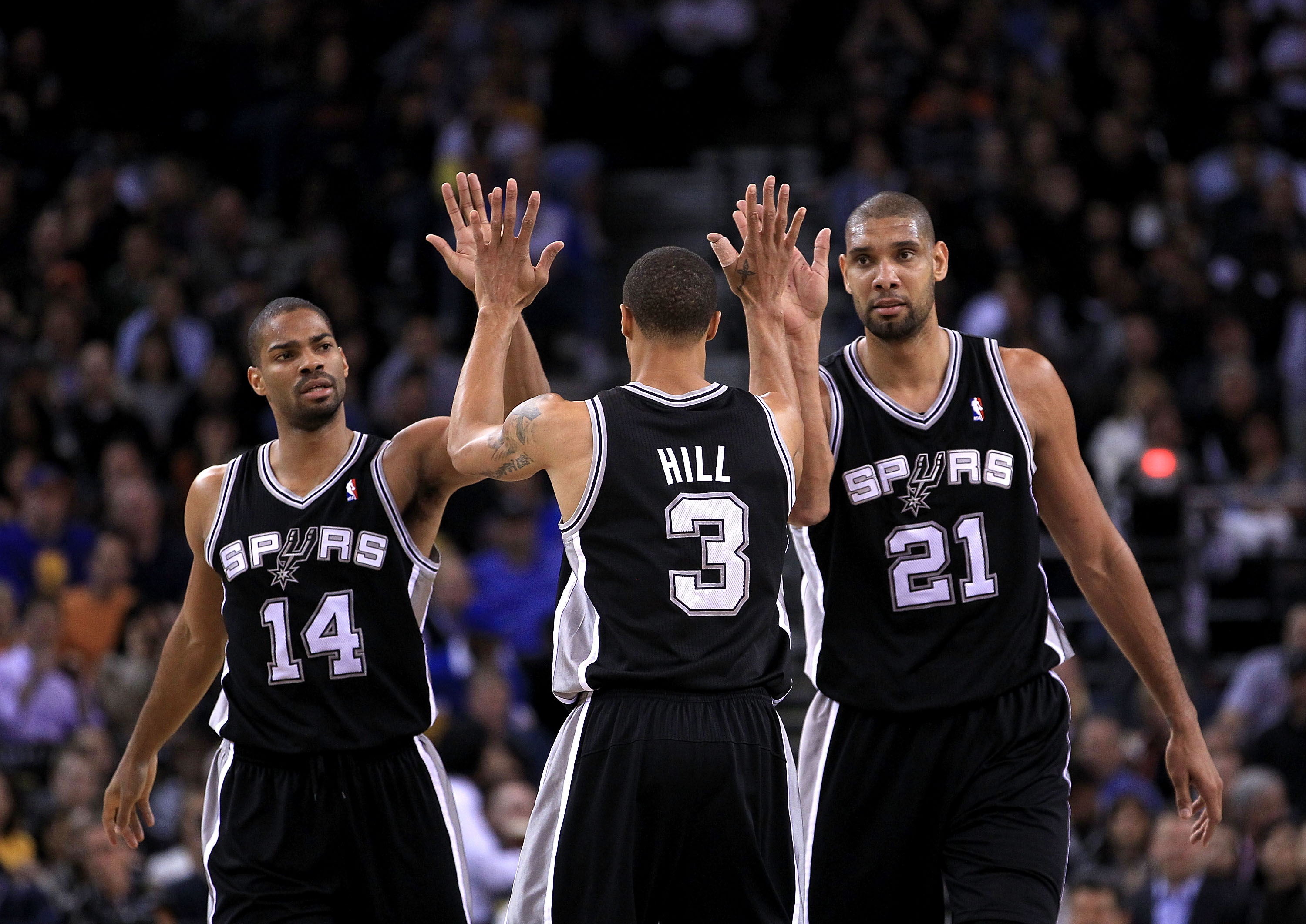 OAKLAND, CA - JANUARY 24:  George Hill #3 of the San Antonio Spurs is congratulated by Tim Duncan #21 and Gary Neal #14 after Hill got fouled during their game against the Golden State Warriors at Oracle Arena on January 24, 2011 in Oakland, California.