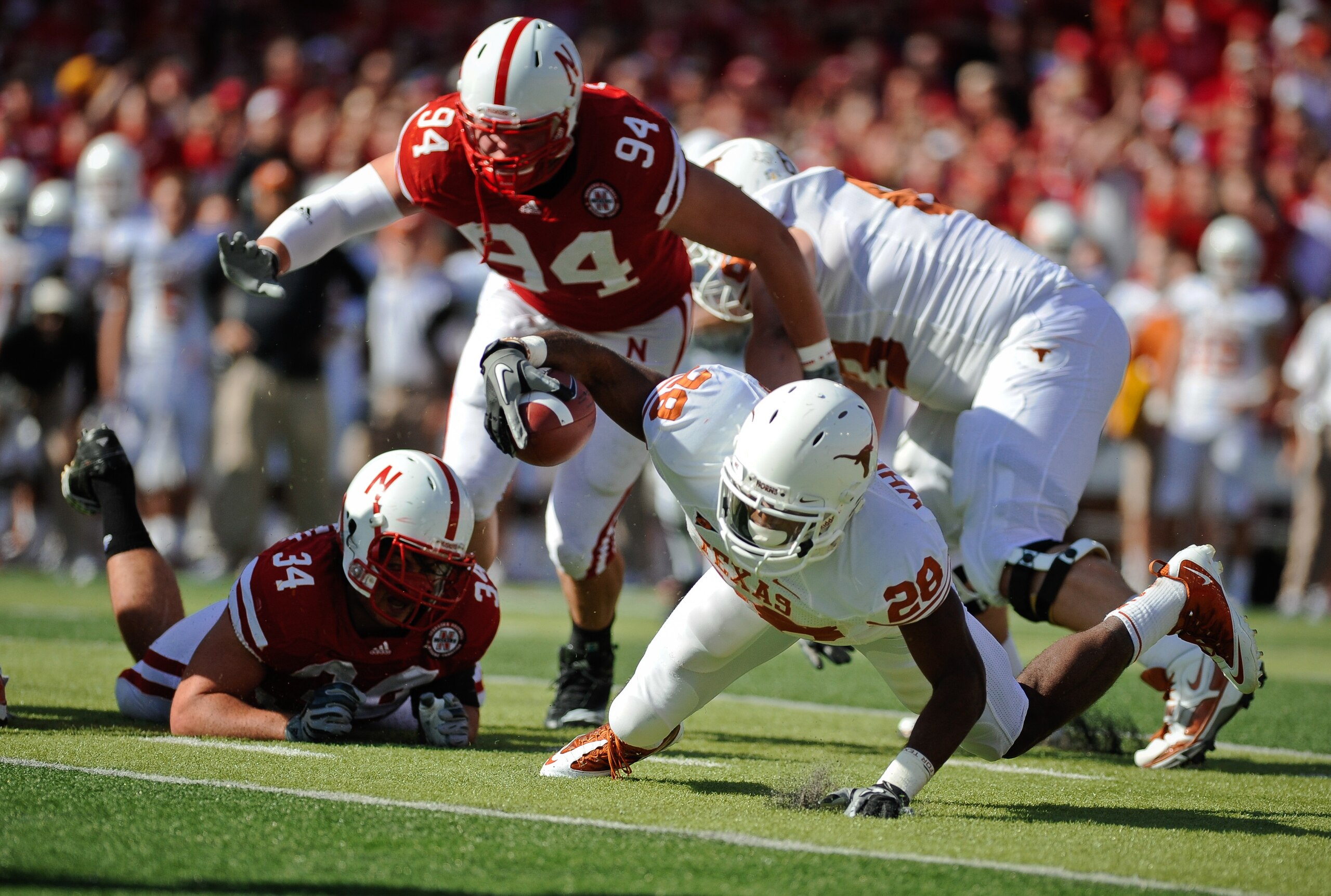 LINCOLN, NE - OCTOBER 16: Texas Longhorn running back Fozzy Whittaker #28 gets tripped up by Nebraska Cornuskers Cameron Meredith #34 and defensive tackle Jared Crick #94 during first half action of their game at Memorial Stadium on October 16, 2010 in Li
