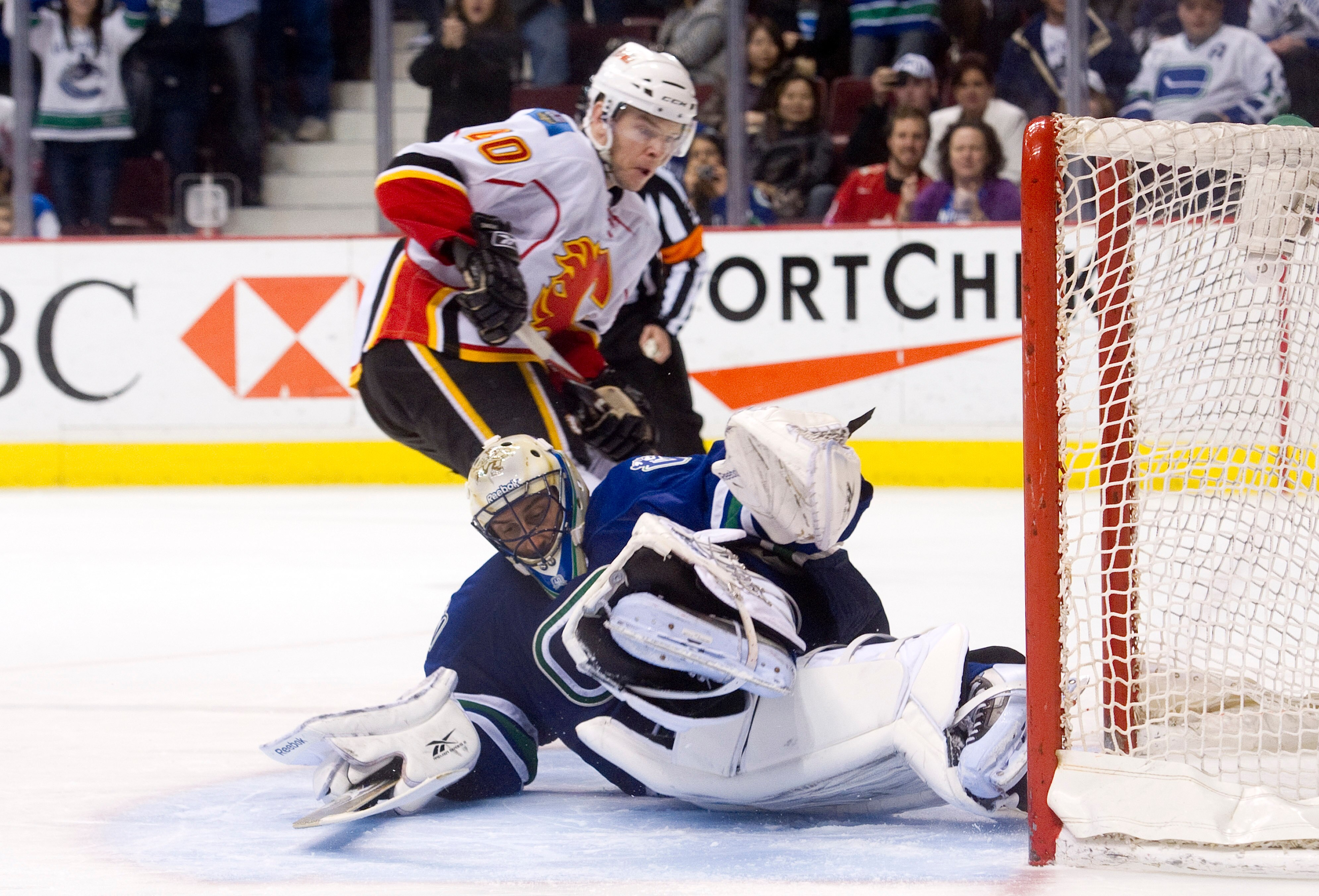 VANCOUVER, CANADA - JANUARY 22: Goalie Roberto Luongo #1 of the Vancouver Canucks stops Alex Tanguay #40 of the Calgary Flames but slides into the net during the shootout in NHL action on January 22, 2011 at Rogers Arena in Vancouver, British Columbia, Ca