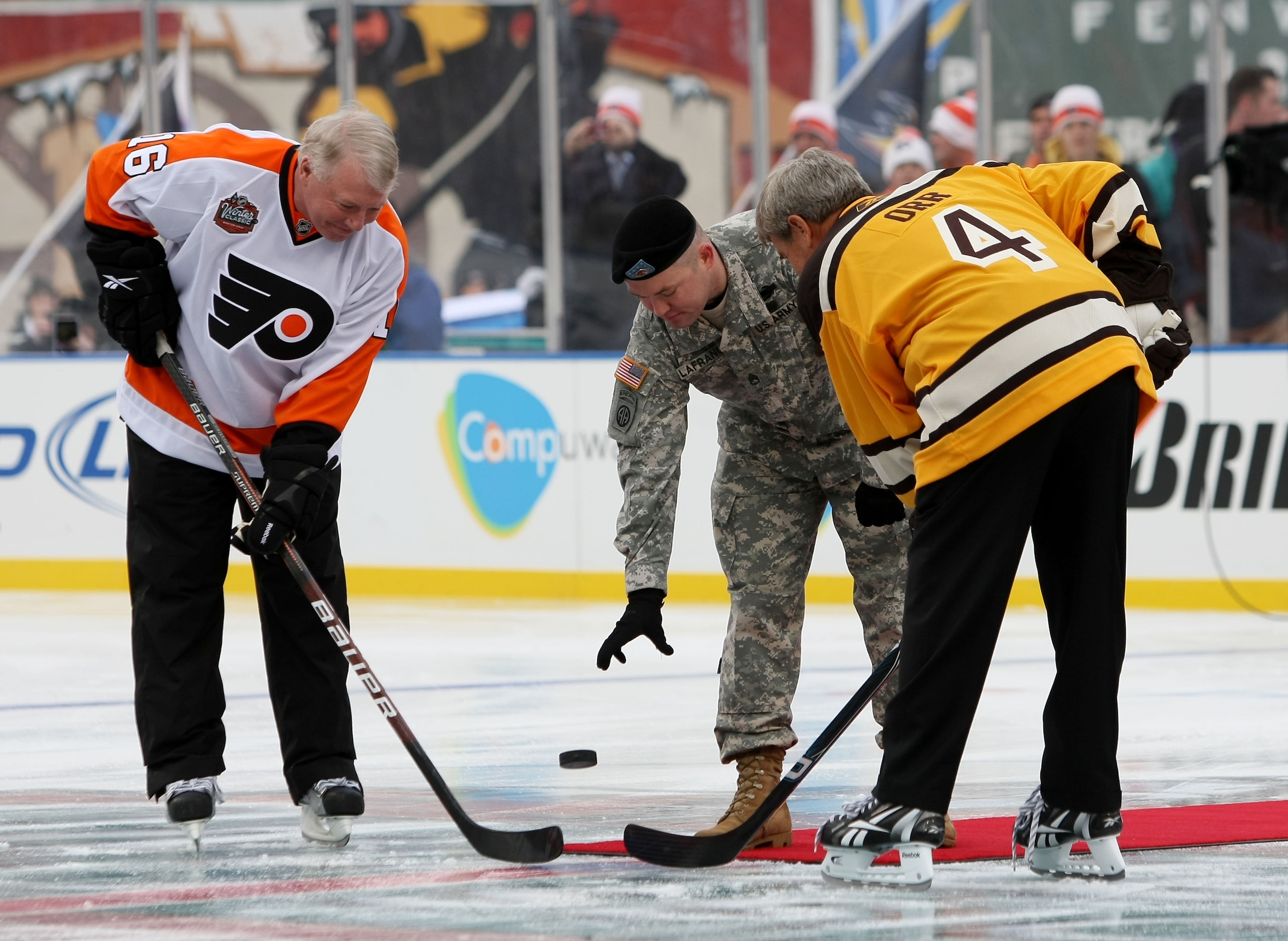 BOSTON - JANUARY 01:  Staff Sergeant Ryan R. LaFrance (C) drops the ceremonial first puck for Bobby Clarke #16 (L) honorary captain of the Philadelphia Flyers and Bobby Orr #4 (R) honorary captain of the Boston Bruins during the 2010 Bridgestone Winter Cl
