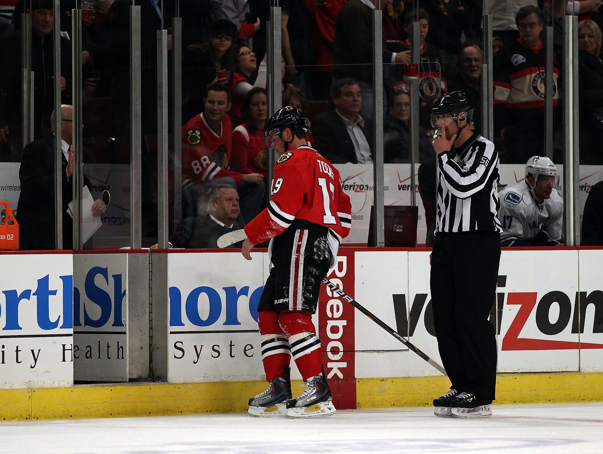 CHICAGO, IL - DECEMBER 03: Jonathan Toews #19 of the Chicago Blackhawks is escorted to the penalty box by a referee during a game against the Vancouver Canucks at the United Center on December 3, 2010 in Chicago, Illinois. The Canucks defeated the Blackha