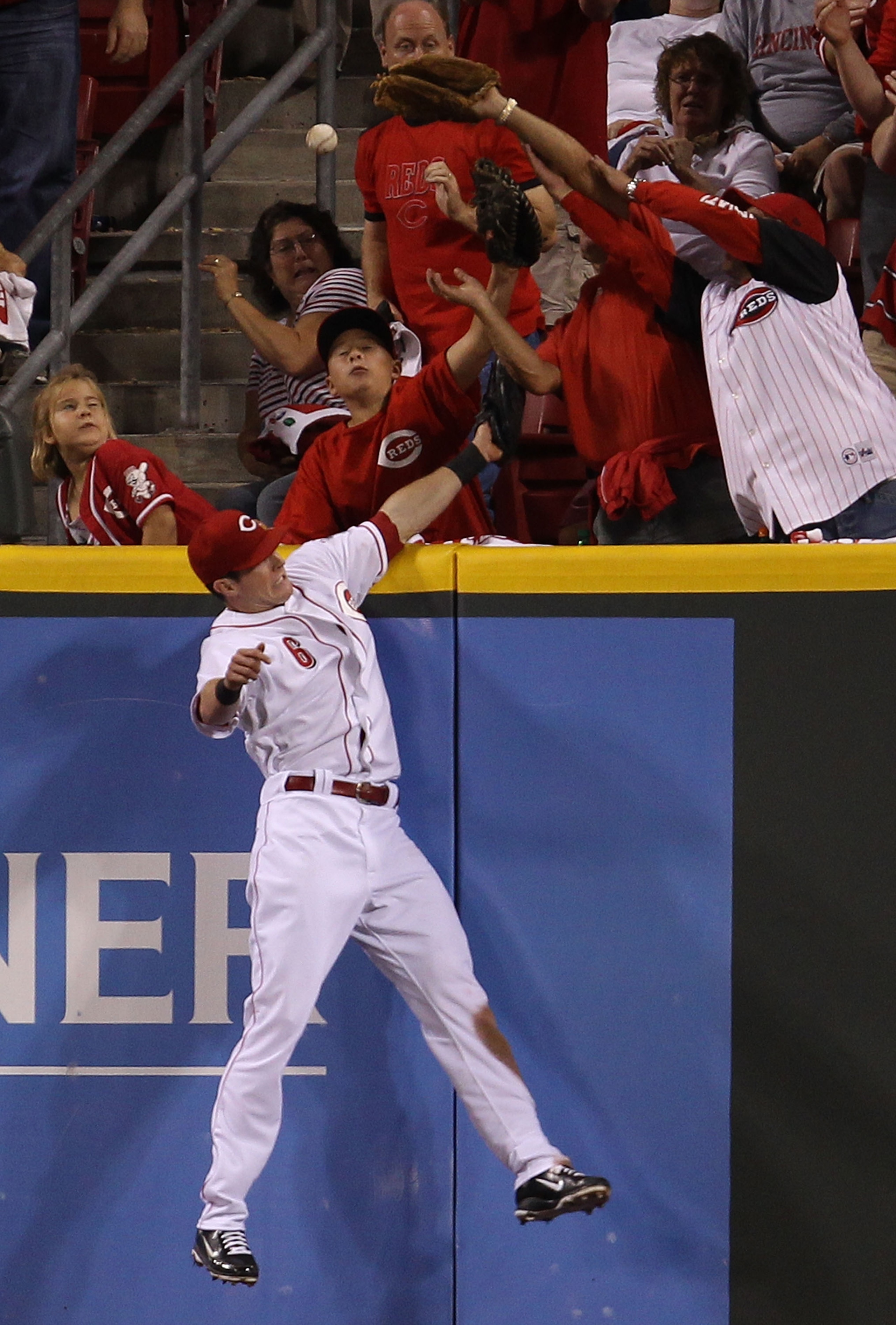 CINCINNATTI - OCTOBER 10: Drew Stubbs #6 of the Cincinnati Reds leaps to try and catch a home run ball hit by Chase Utley of the Philadelphia Phillies during game 3 of the NLDS at Great American Ball Park on October 10, 2010 in Cincinnati, Ohio. (Photo by