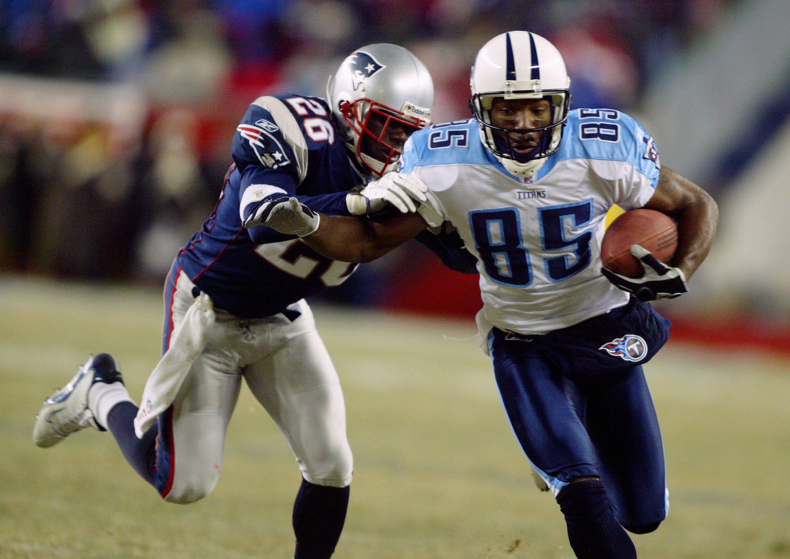 FOXBORO, MA - JANUARY 10:  Wide receiver Derrick Mason #85 of the Tennessee Titans tries to break a tackle by Eugene Wilson #85 of the New England Patriots in the AFC divisional playoffs on January 10, 2004 at Gillette Stadium in Foxboro, Massachusetts. T