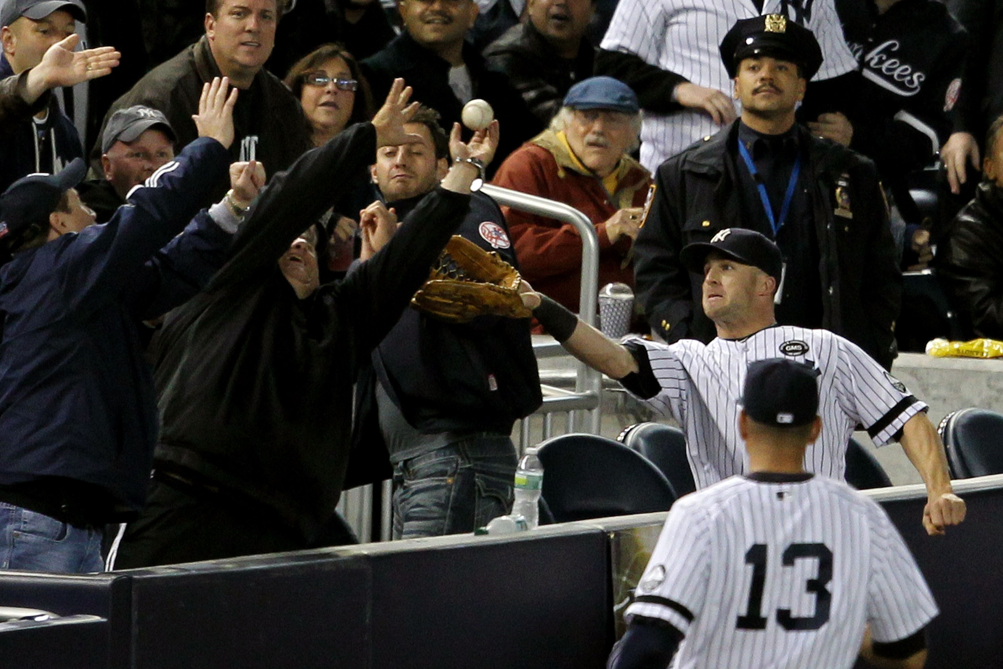 NEW YORK - OCTOBER 19:  Brett Gardner #11 of the New York Yankees tries to make a play in foul territory as a fan gets in the way against the Texas Rangers in Game Four of the ALCS during the 2010 MLB Playoffs at Yankee Stadium on October 19, 2010 in the