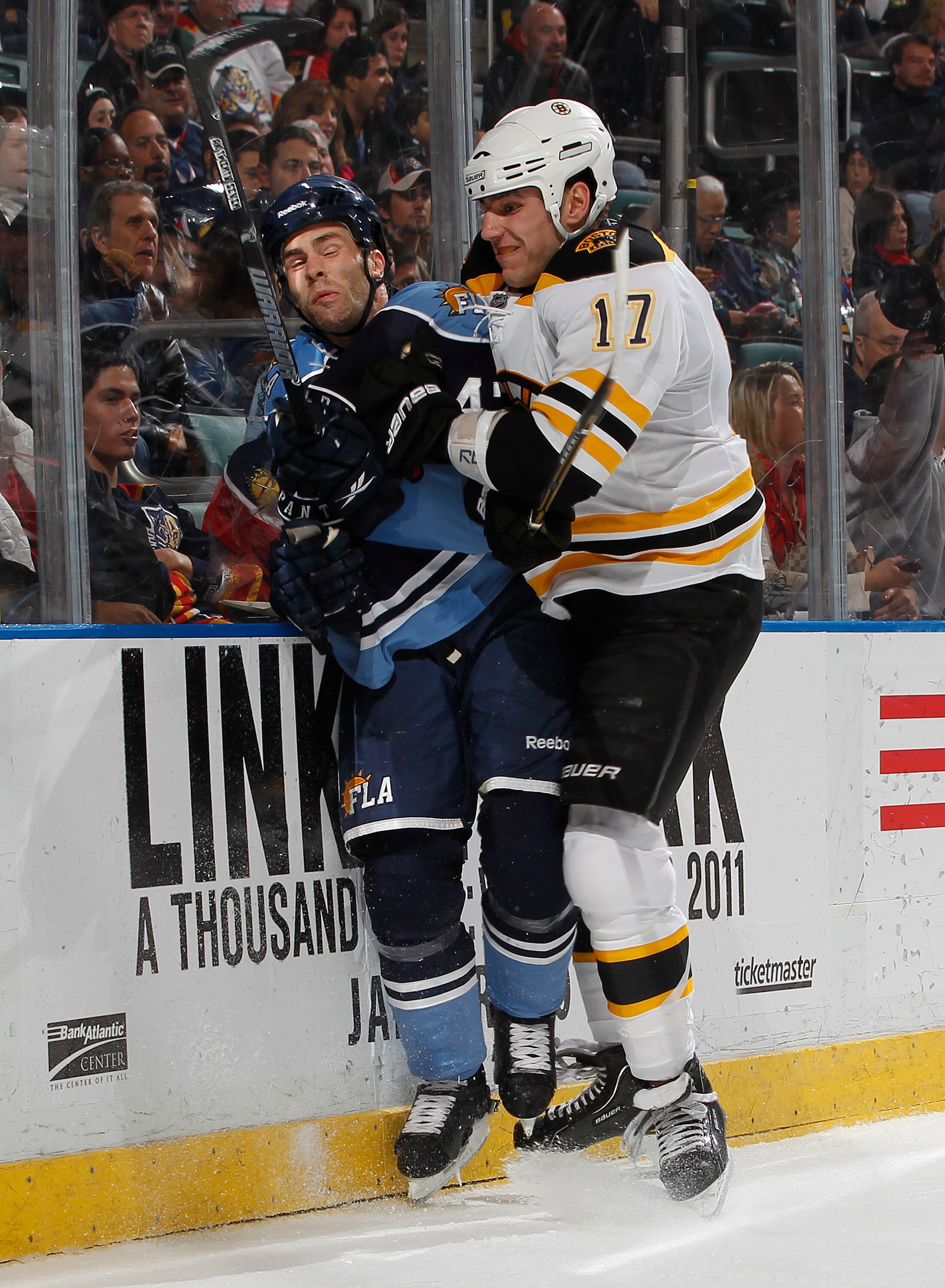 SUNRISE, FL - DECEMBER 27: Mike Weaver #43 of the Florida Panthers is checked into the boards by Milan Lucic #17 of the Boston Bruins on December 27, 2010 at the BankAtlantic Center in Sunrise, Florida. The Bruins defeated the Panthers 3-2 in a shoot-out.