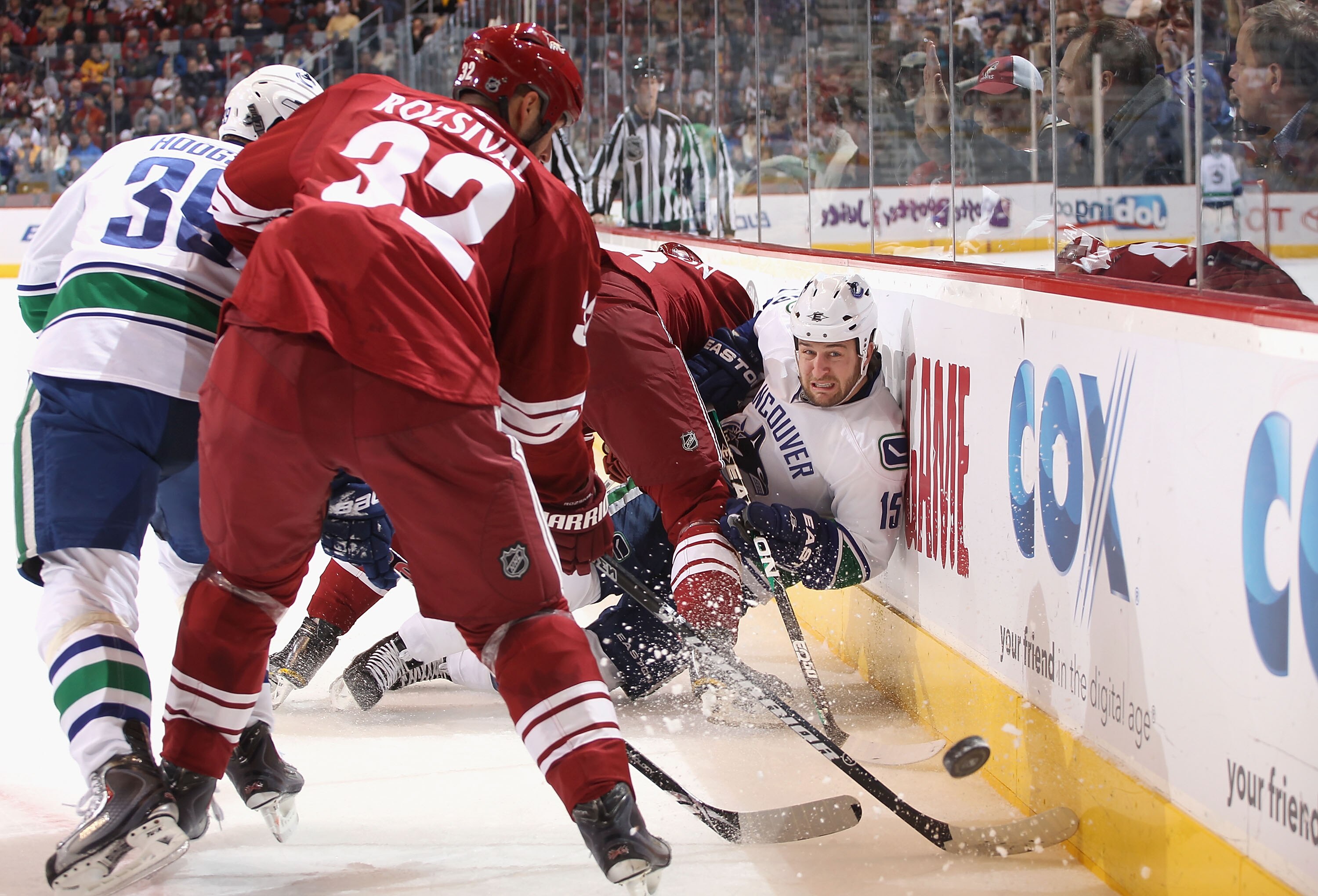 GLENDALE, AZ - FEBRUARY 02:  Tanner Glass #15 of the Vancouver Canucks moves the puck into the corner as he is hit into the boards during the NHL game against the Phoenix Coyotes at Jobing.com Arena on February 2, 2011 in Glendale, Arizona.  (Photo by Chr