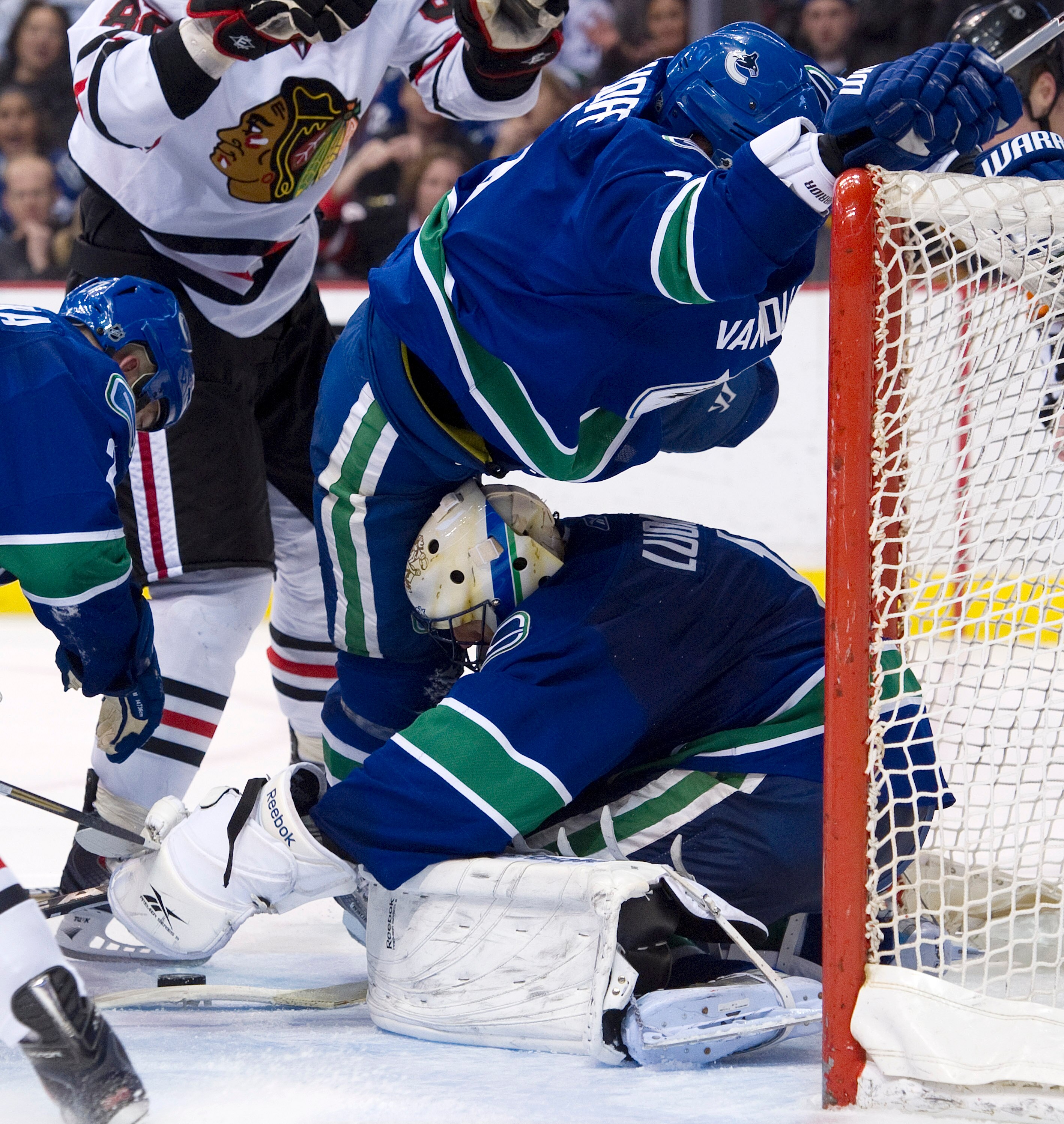VANCOUVER, CANADA - JANUARY 4: Goalie Roberto Luongo #1 of the Vancouver Canucks searches for the loose puck while Christian Ehrhoff #5 tries not to fall on top of his goalie during the third period in NHL action against the Chicago Blackhawks on February