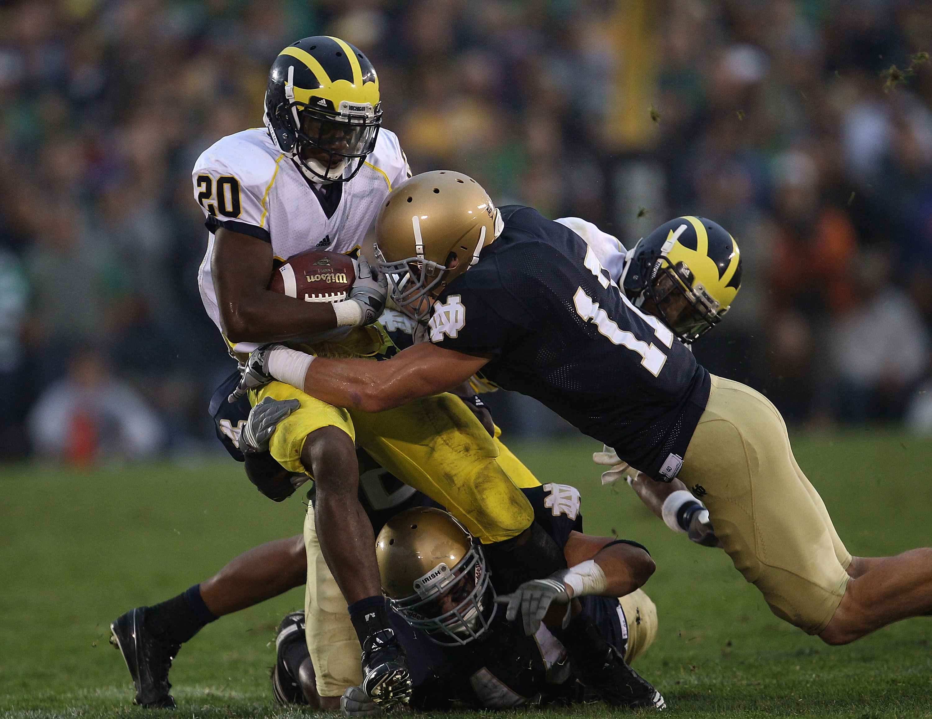 SOUTH BEND, IN - SEPTEMBER 11: Michael Shaw #20 of the Michigan Wolverines is tackled by Carlo Calabrese #44 and Zeke Motta #17 of the Notre Dame Fighting Irish at Notre Dame Stadium on September 11, 2010 in South Bend, Indiana. Michigan defeated Notre Da