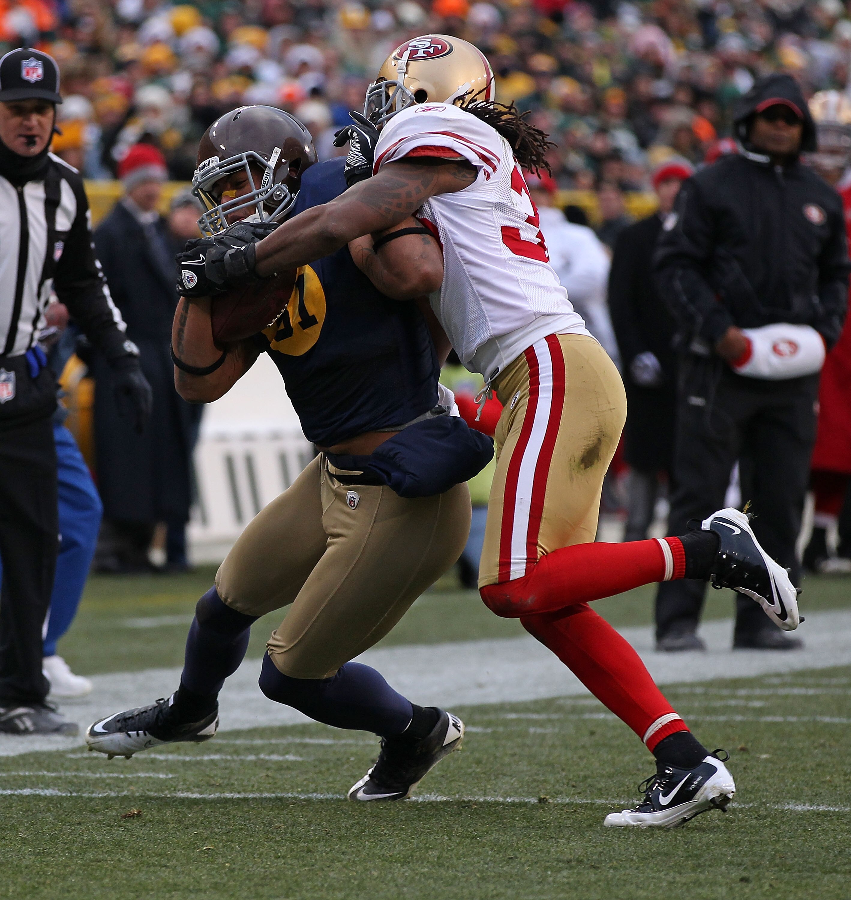 GREEN BAY, WI - DECEMBER 05: Dashon Goldson #38 of the San Francisco 49ers tackles Andrew Quarless #81 of the Green Bay Packers at Lambeau Field on December 5, 2010 in Green Bay, Wisconsin. The Packers defeated the 49ers 34-16. (Photo by Jonathan Daniel/G