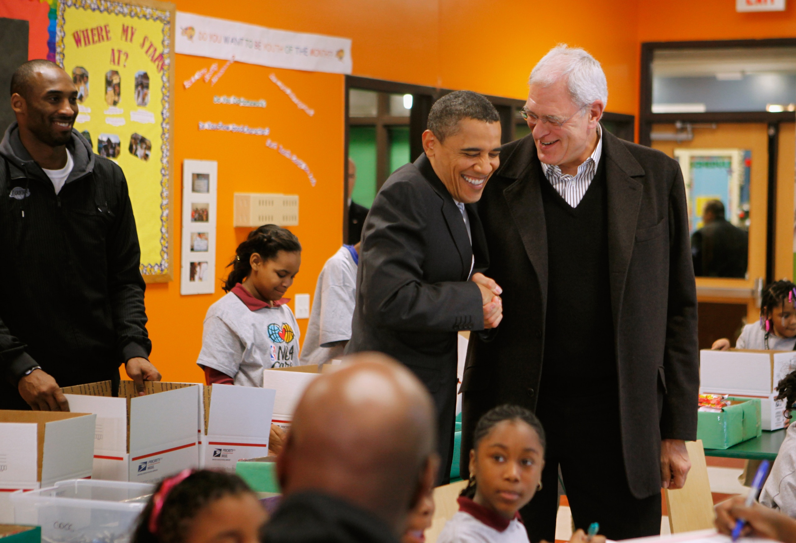 WASHINGTON, DC - DECEMBER 13:  (AFP OUT) U.S. President Barack Obama (C) greets Los Angeles Lakers head coach Phil Jackson (R) while helping children volunteers fill care packages during a NBA Cares service event at the Boys and Girls Club at THEARC   Dec