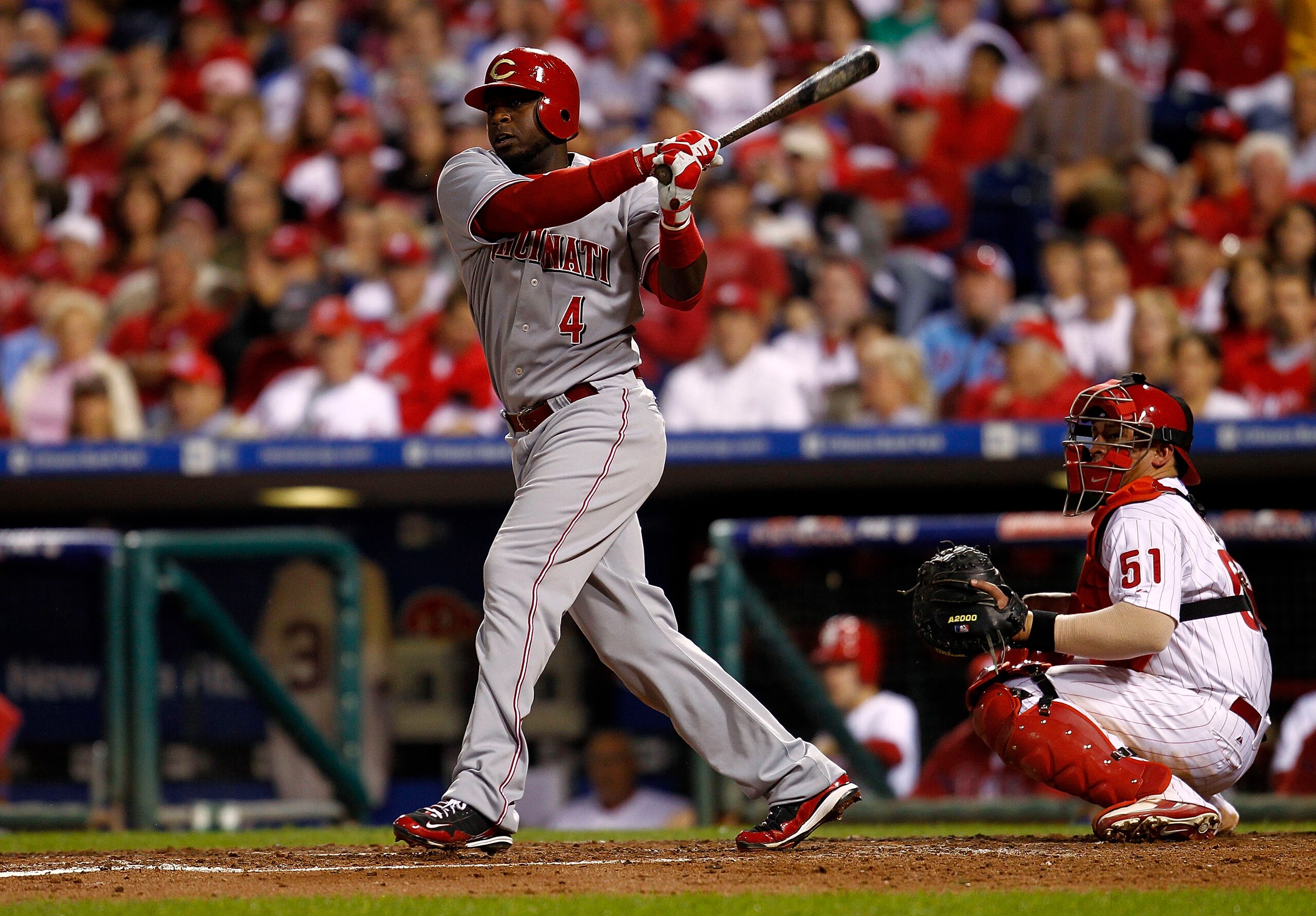 PHILADELPHIA - OCTOBER 08:  Brandon Phillips #4 of the Cincinnati Reds doubles in Game 2 of the NLDS in front of Carlos Ruiz #51 of the Philadelphia Phillies at Citizens Bank Park on October 8, 2010 in Philadelphia, Pennsylvania.  (Photo by Jeff Zelevansk