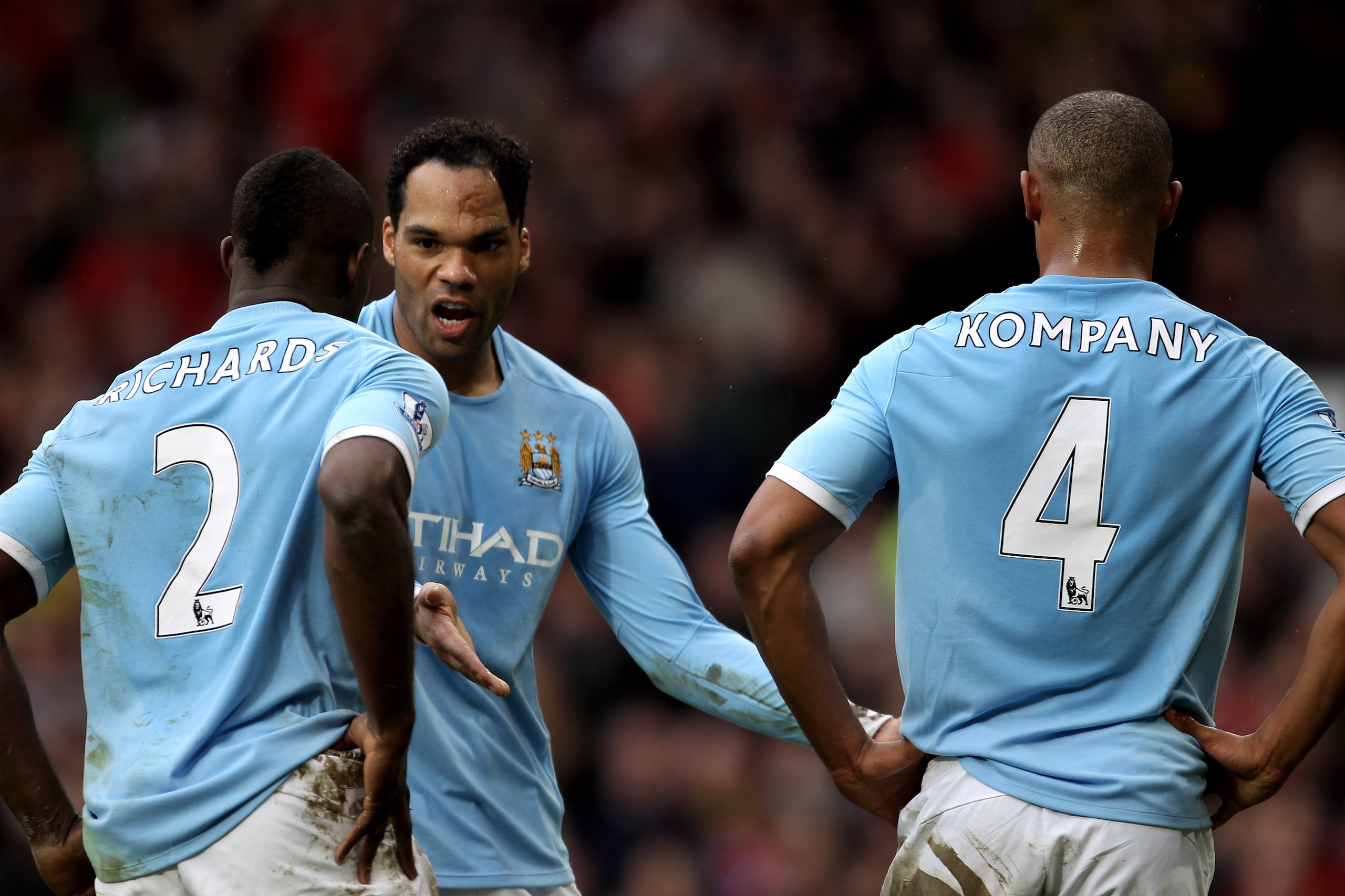 MANCHESTER, ENGLAND - FEBRUARY 12:  Joleon Lescott (C) of Manchester City has words with teammates Micah Richards (L) and Vincent Kompany (R) during the Barclays Premier League match between Manchester United and Manchester City at Old Trafford on Februar